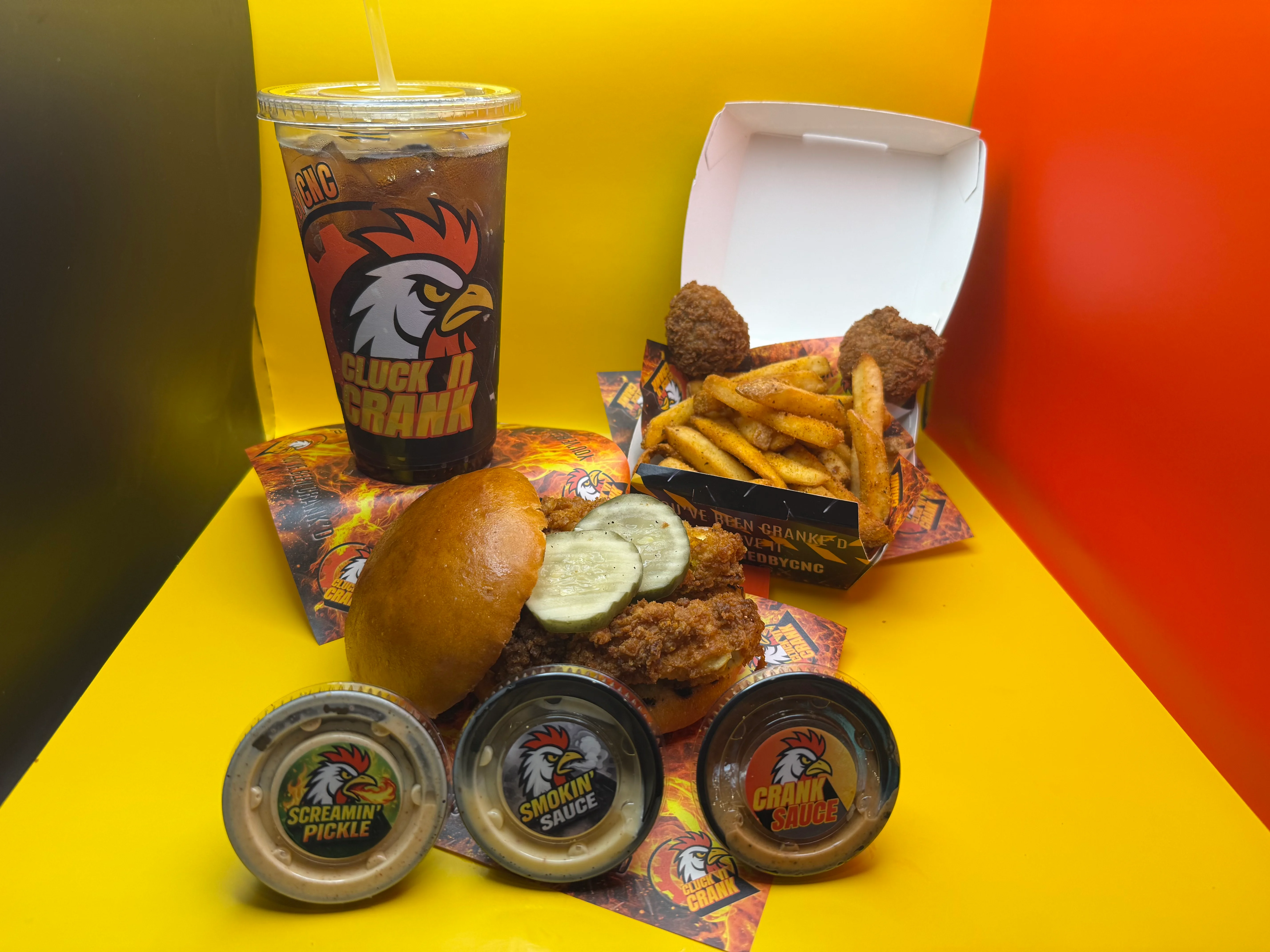 A meal from Cluck 'n Crank featuring chicken sandwich, fries, and sauces.