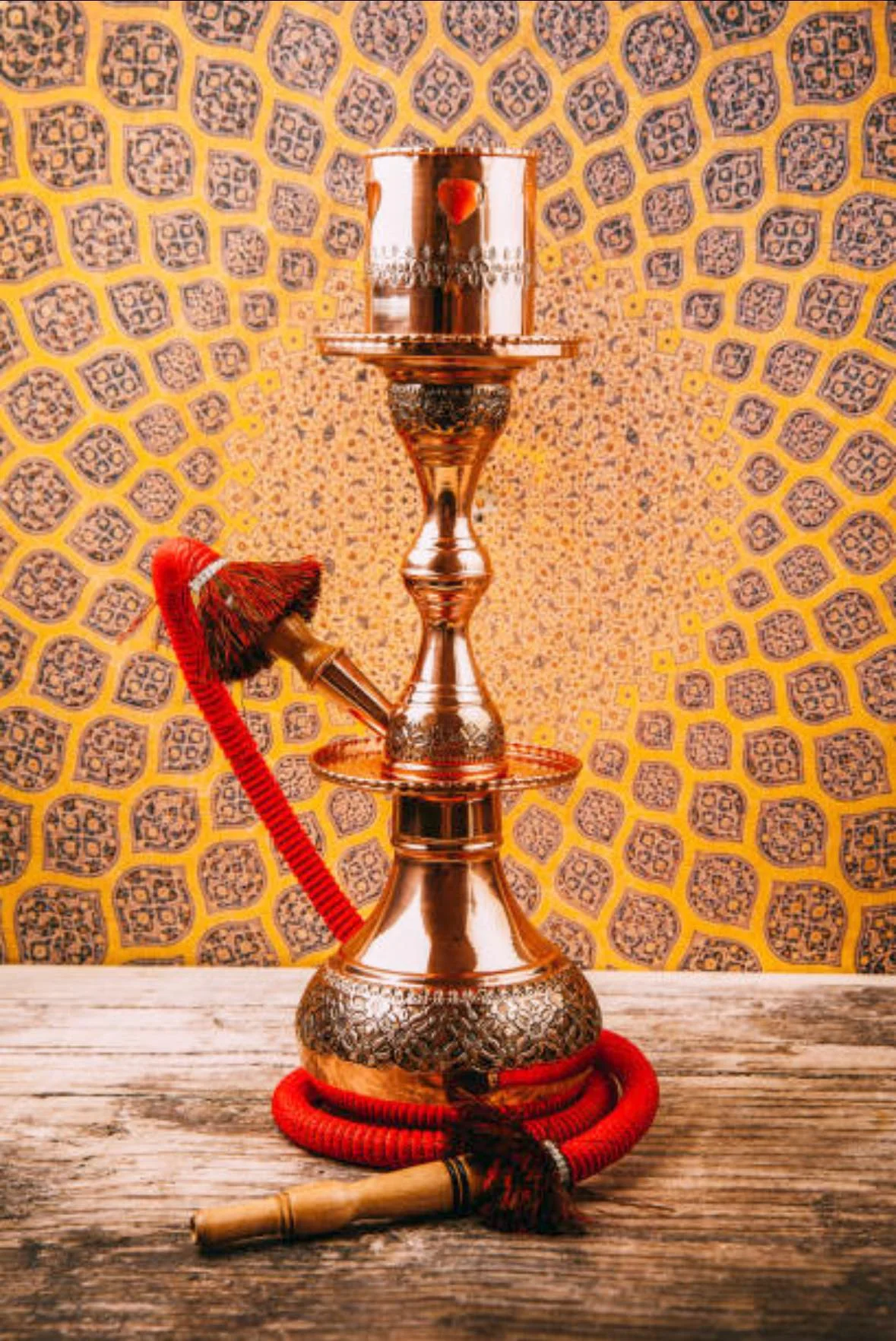 A beautifully crafted hookah placed against a vibrant patterned background.