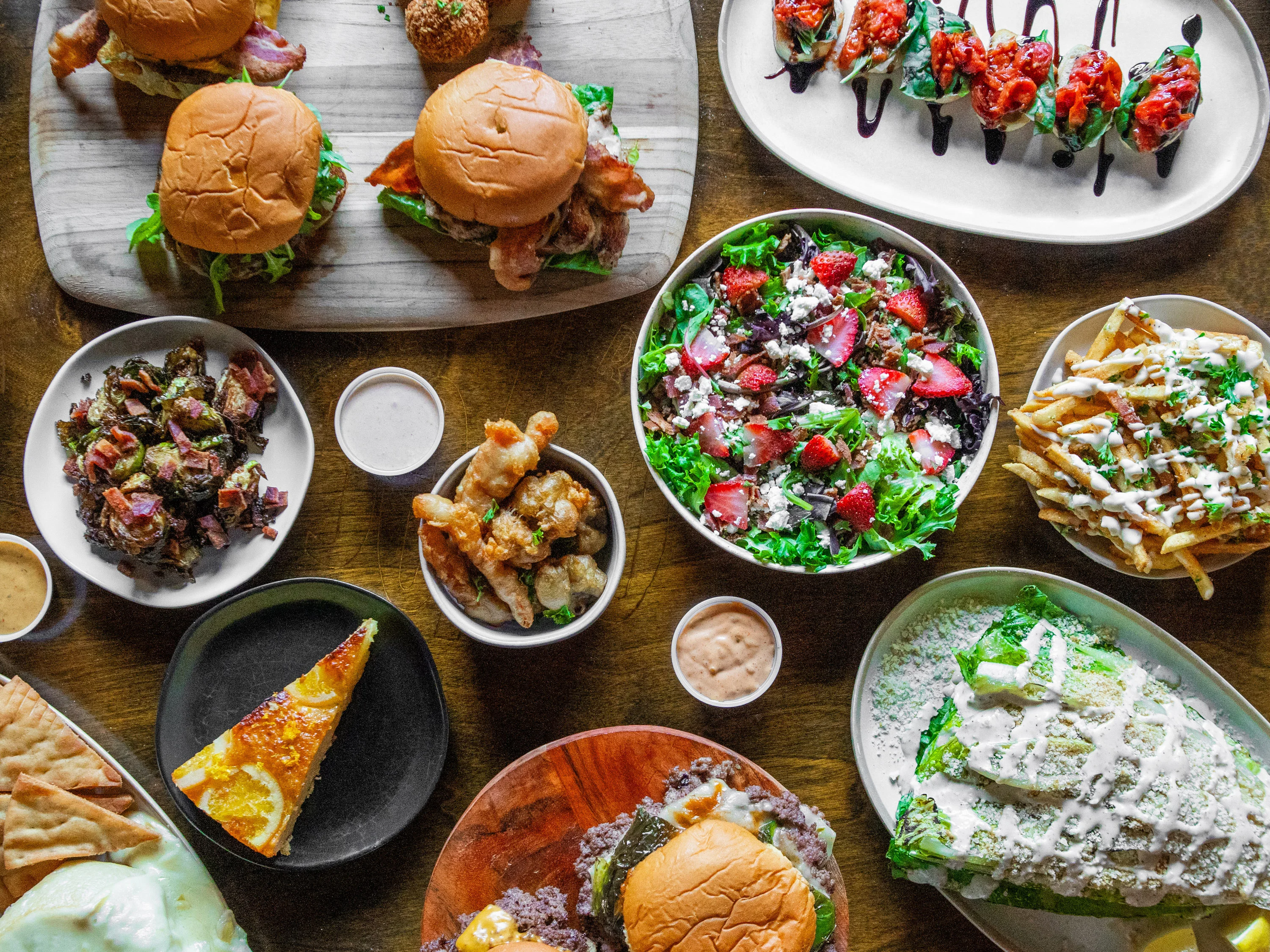 Assorted American comfort food platter with burgers, salads, and fries