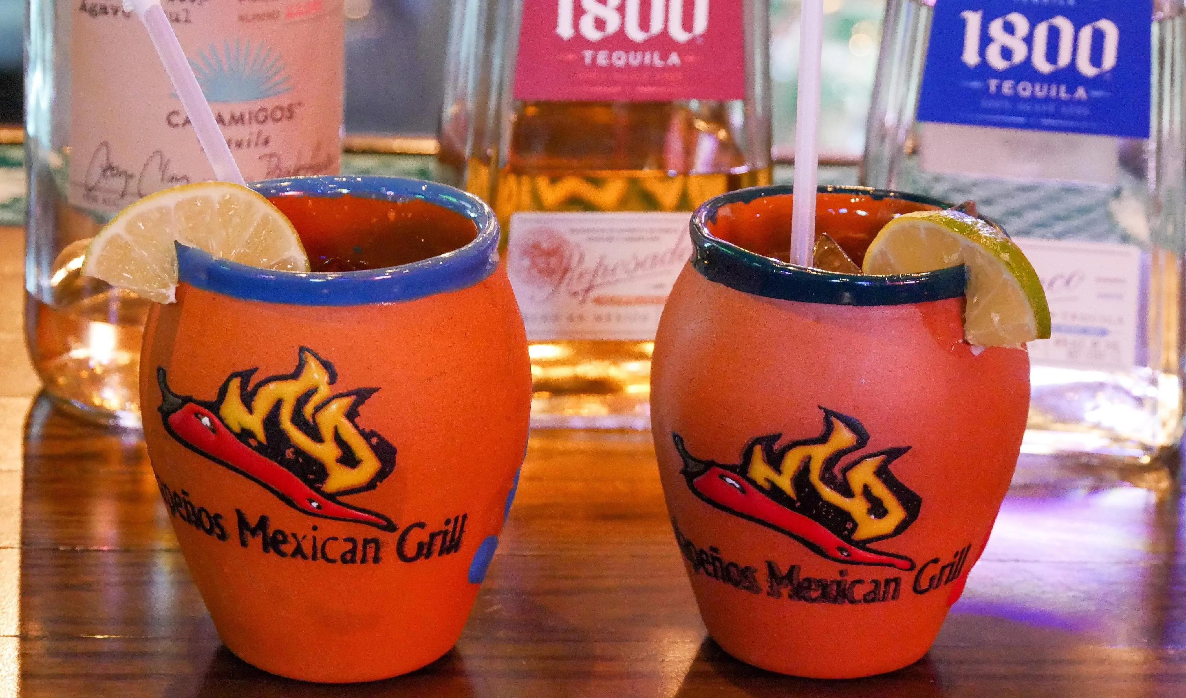 Colorful Mexican cocktails with lime in traditional clay mugs