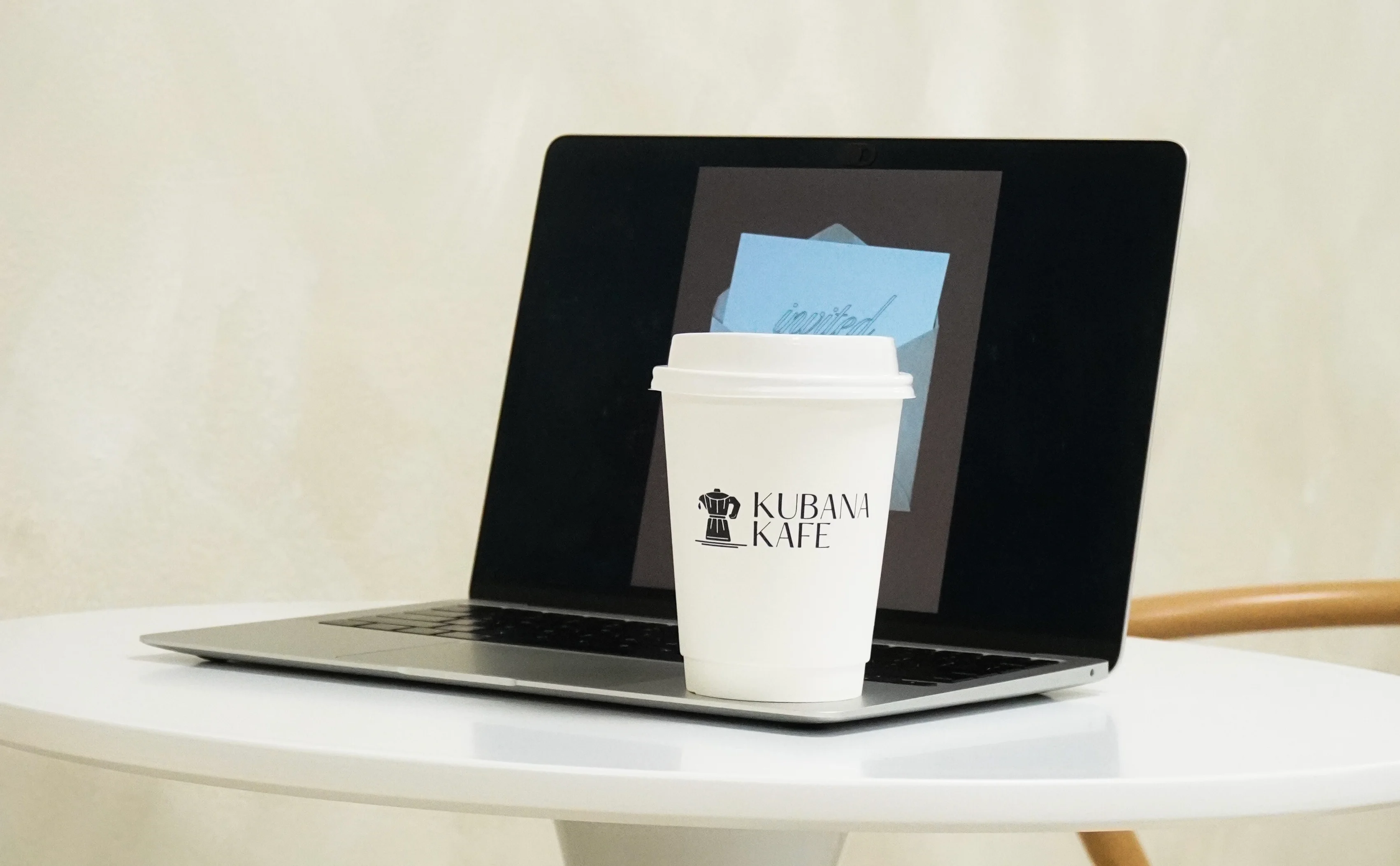 Coffee cup on a table with a laptop in a cozy cafe setting
