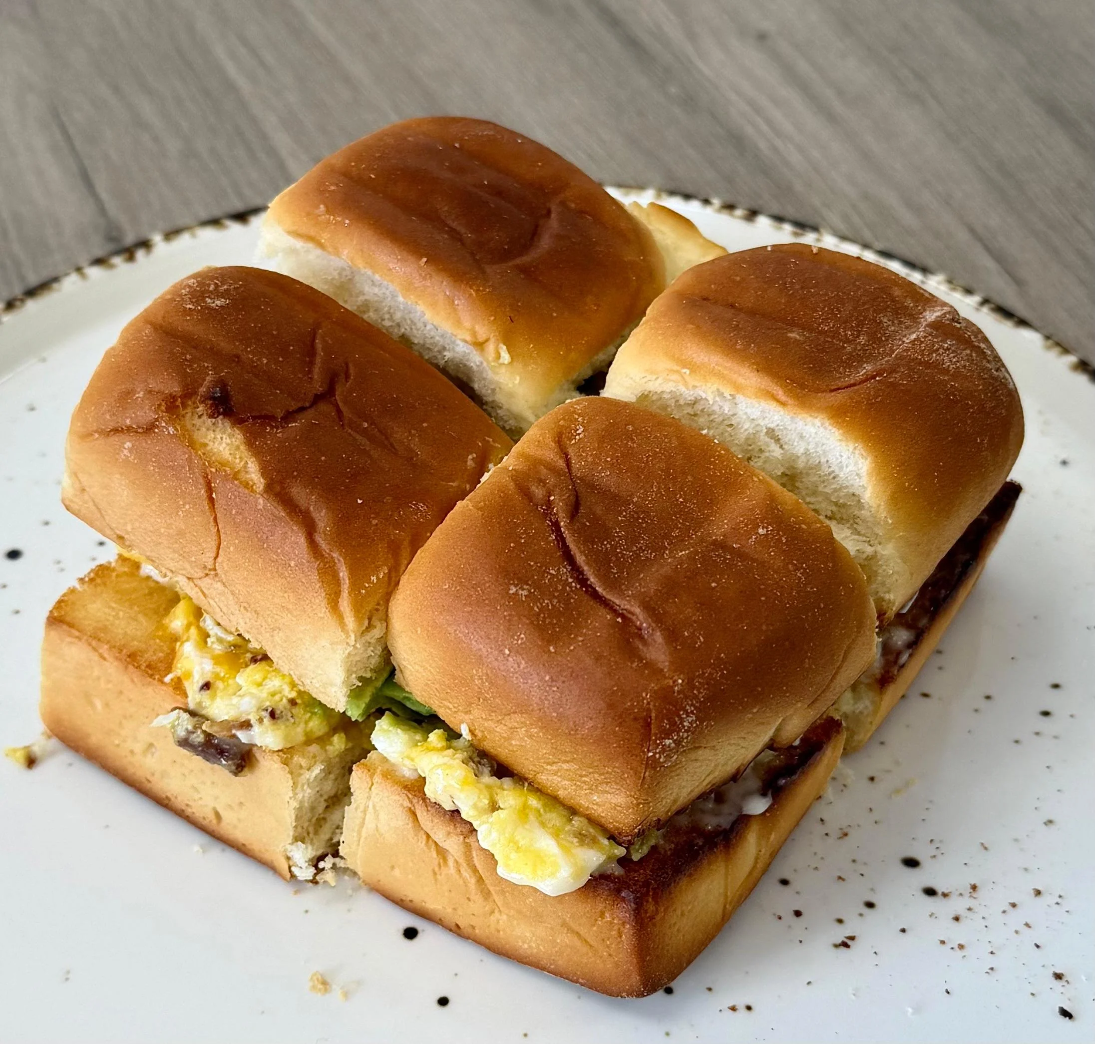 A serving of soft rolls, filled with scrambled eggs and greens, displayed on a decorative plate.