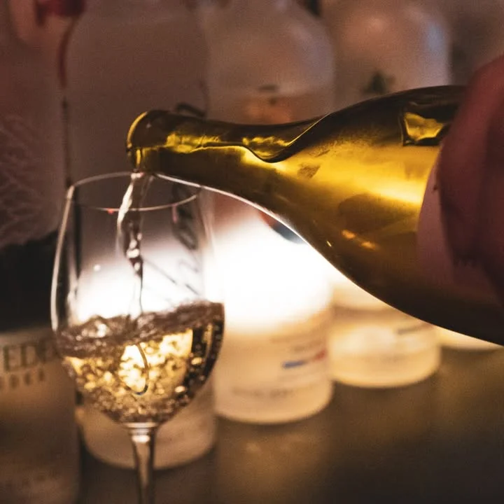 Pouring sparkling wine into a glass with soft lighting in the background