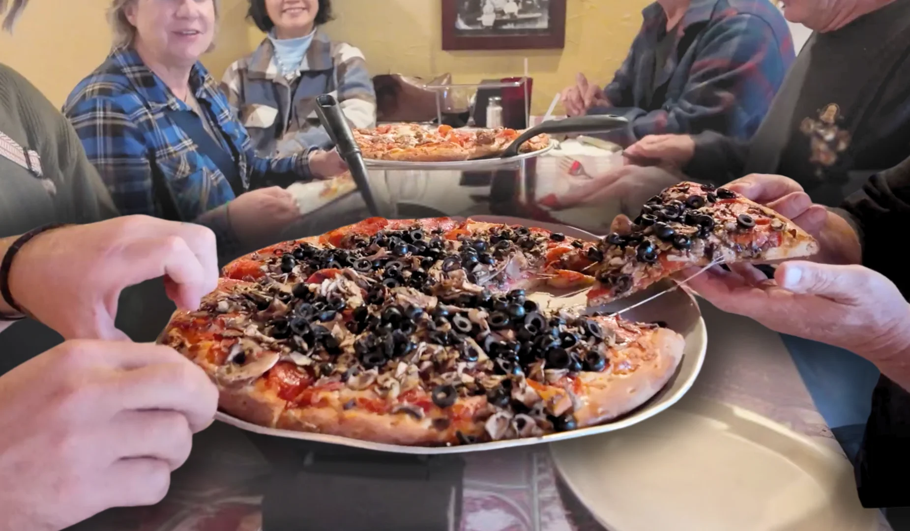 Delicious pepperoni pizza topped with black olives in a cozy restaurant setting