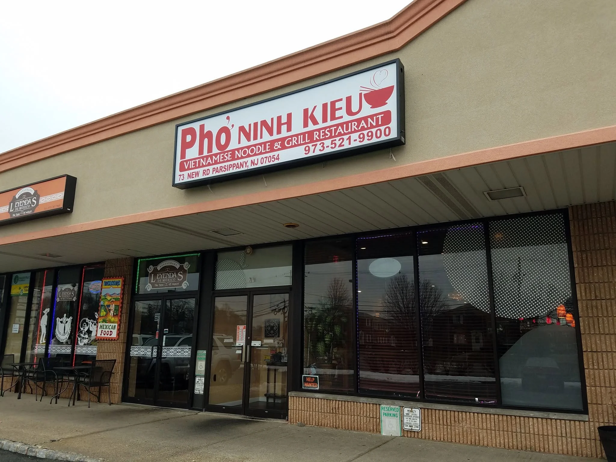 A storefront view of a Vietnamese noodle and grill restaurant, featuring a sign with the name and contact information.