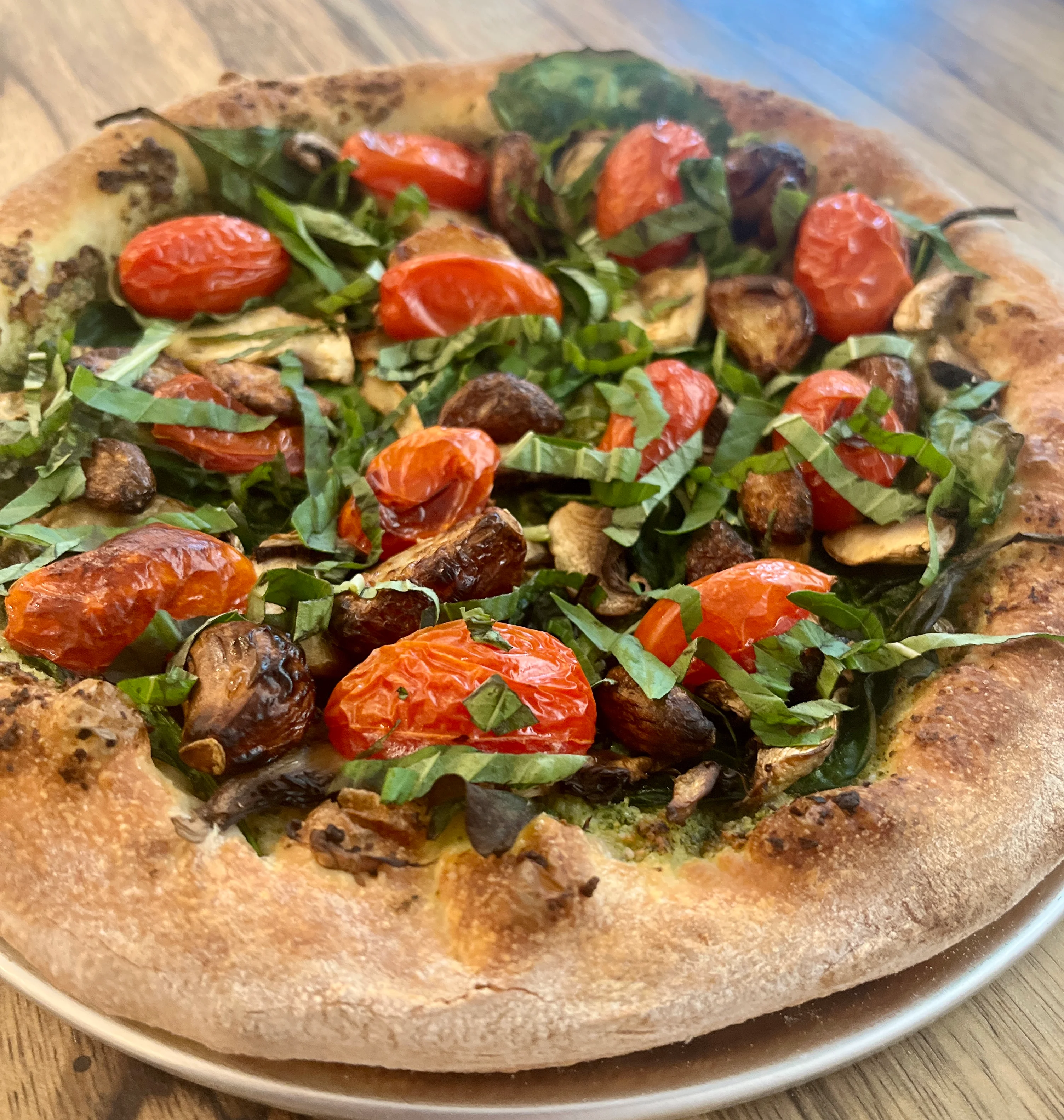 Vegetarian pizza topped with fresh basil and roasted tomatoes
