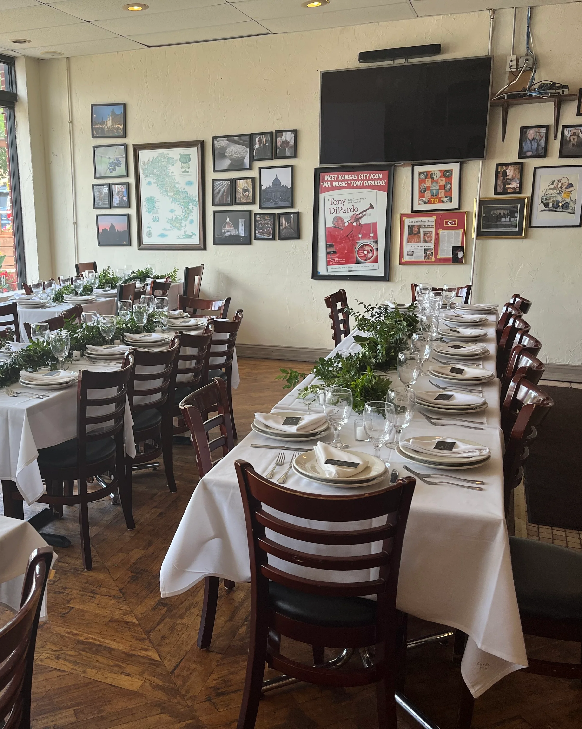 Elegant restaurant dining setup with white tablecloths and greenery