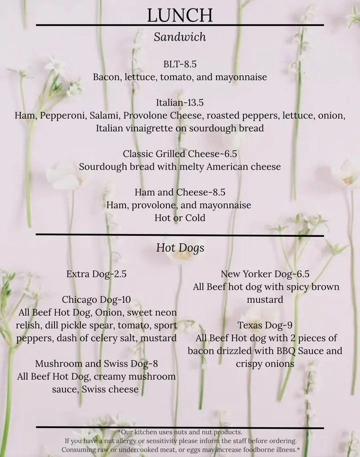 A lunch menu featuring various sandwiches and hot dogs with detailed descriptions and prices. The background has a soft floral design, adding a delicate touch to the presentation.
