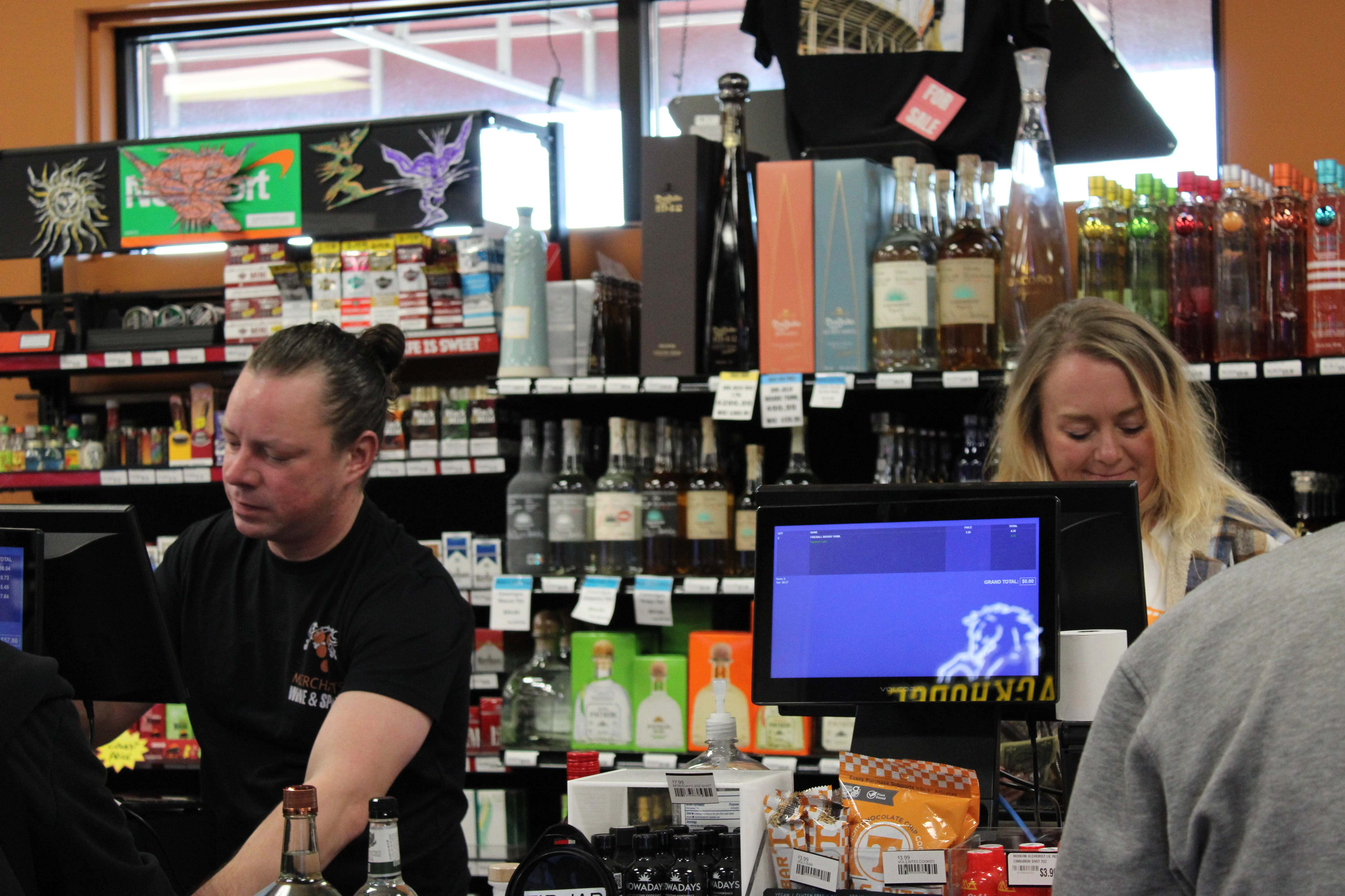 Staff serving customers at a liquor store checkout counter
