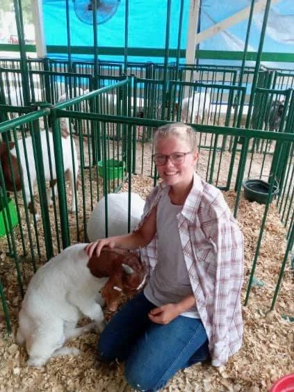 Young woman interacting with goats in a farm setting