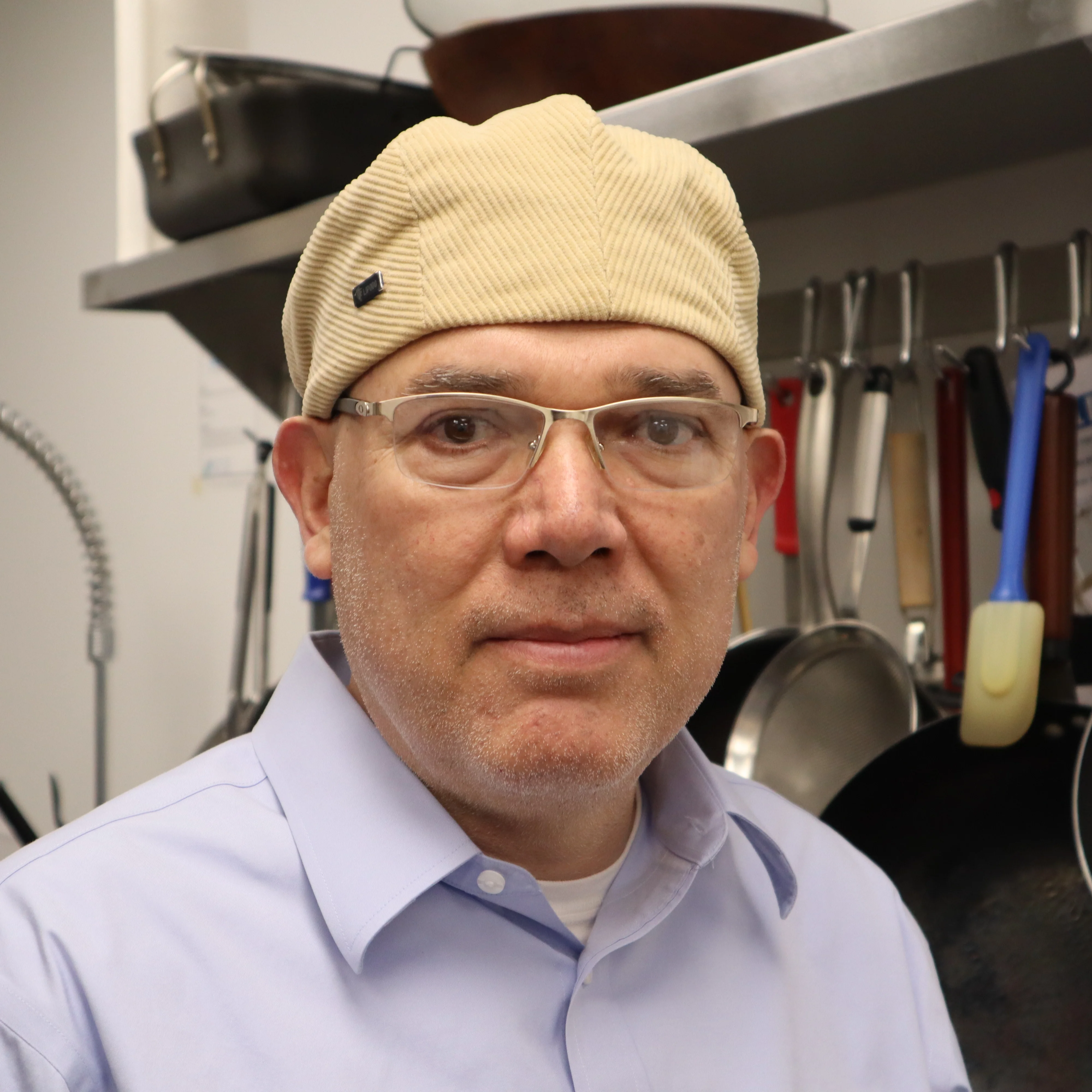 Chef in a professional kitchen wearing a hat and glasses
