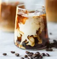 Iced coffee with cream swirling in a glass