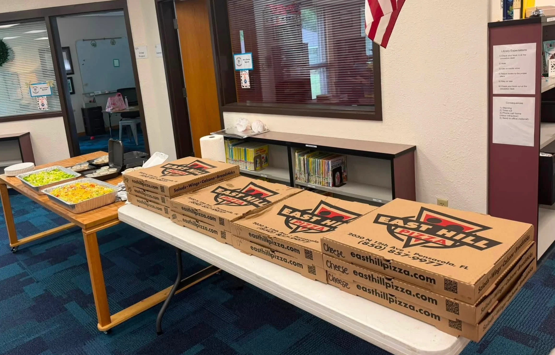 Pizza catering spread with boxed pizzas and salad trays at a community event