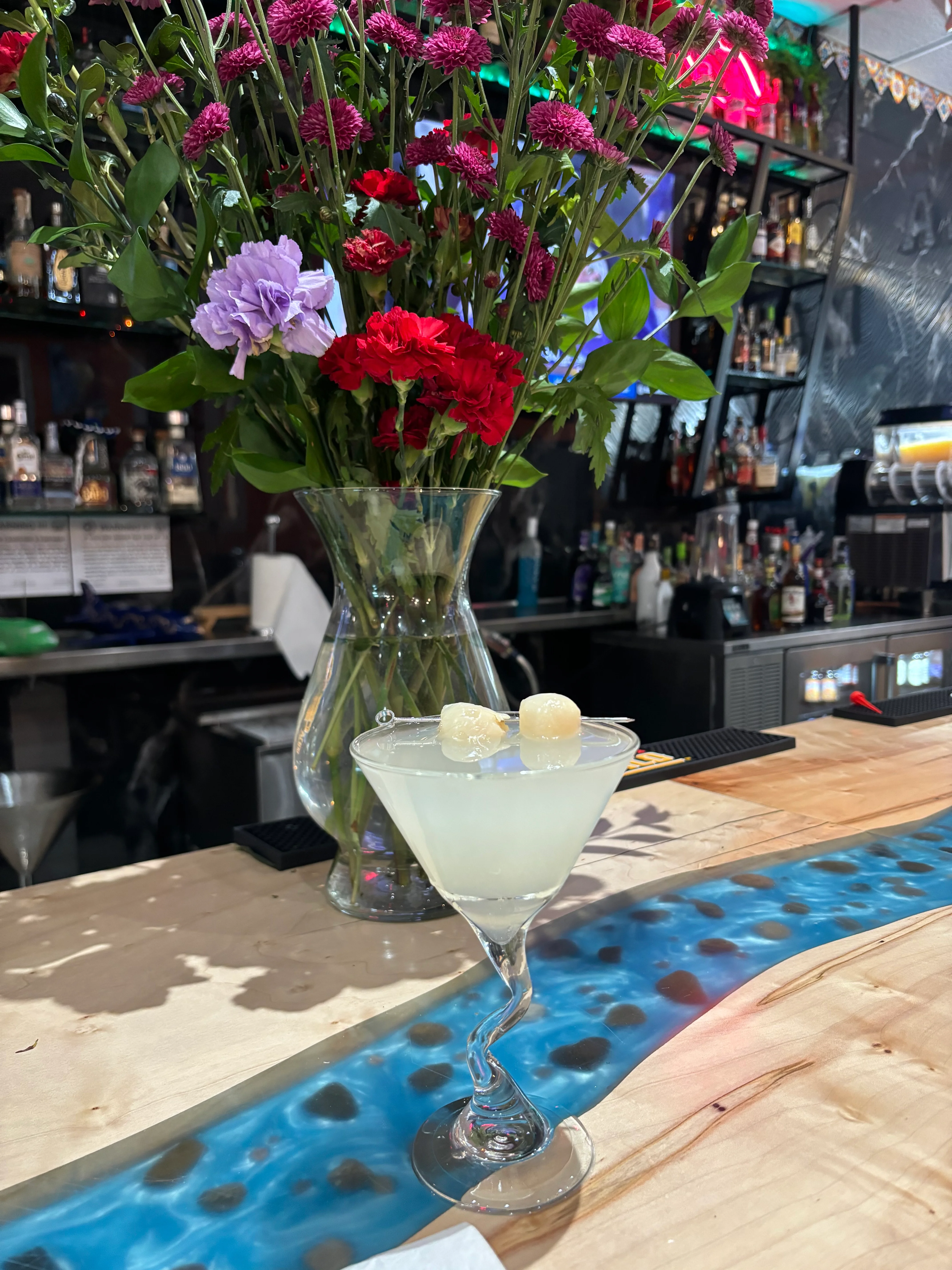 Refreshing cocktail with floral garnish at a vibrant bar