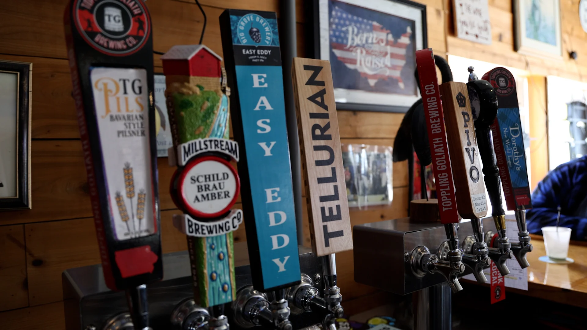 Variety of beer taps featuring local brews in a rustic bar setting.