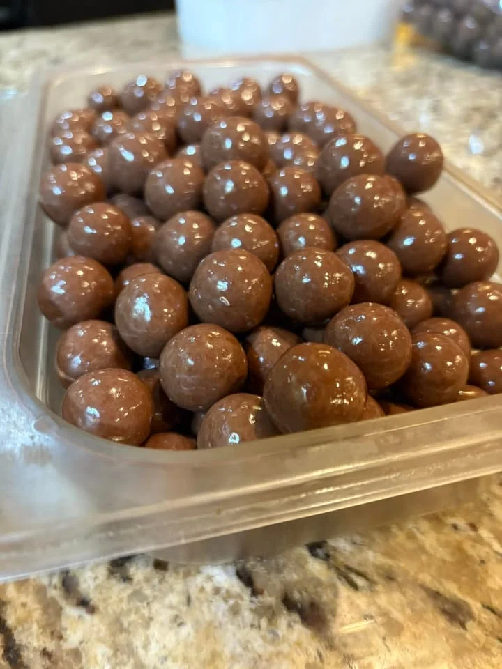 A tray filled with glossy chocolate-covered balls, arranged densely together.