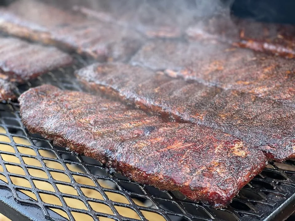 Smoked barbecue ribs on a grill, showcasing a rich, smoky crust