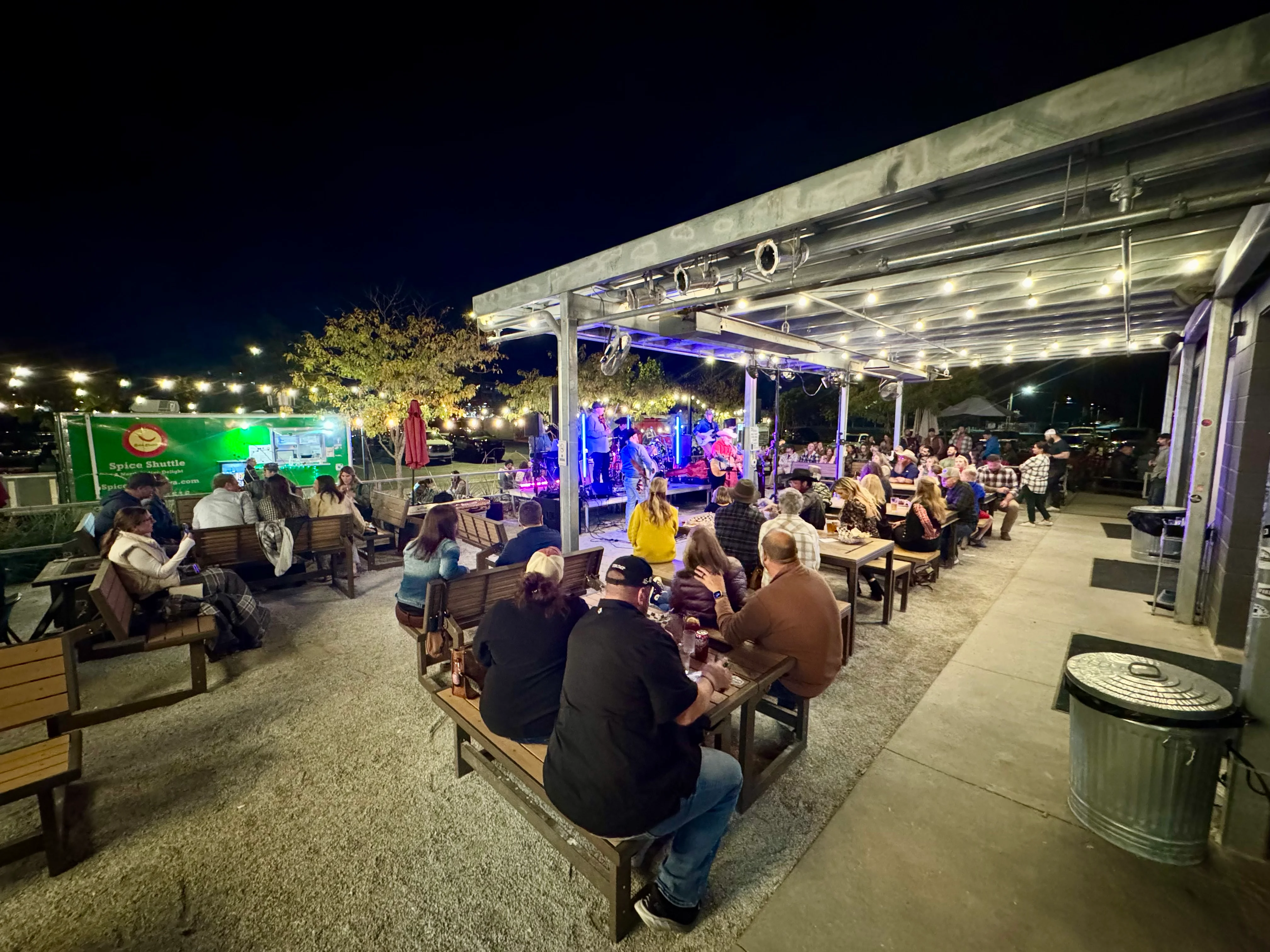 Outdoor dining area with live music and string lights at night.