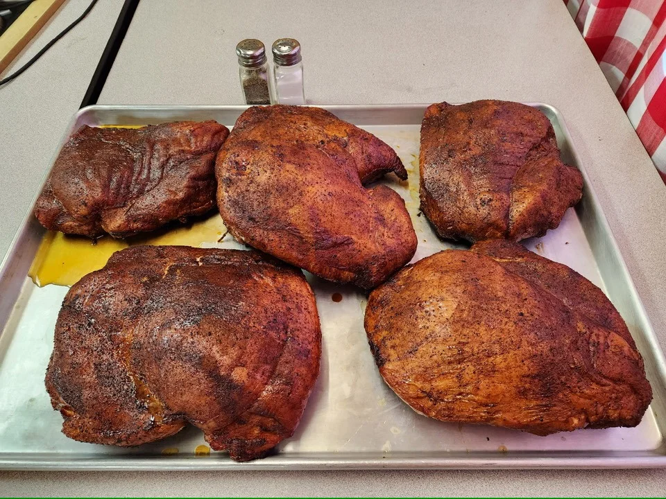 Five pieces of smoked meat arranged on a tray, highlighting their dark, flavorful crust.