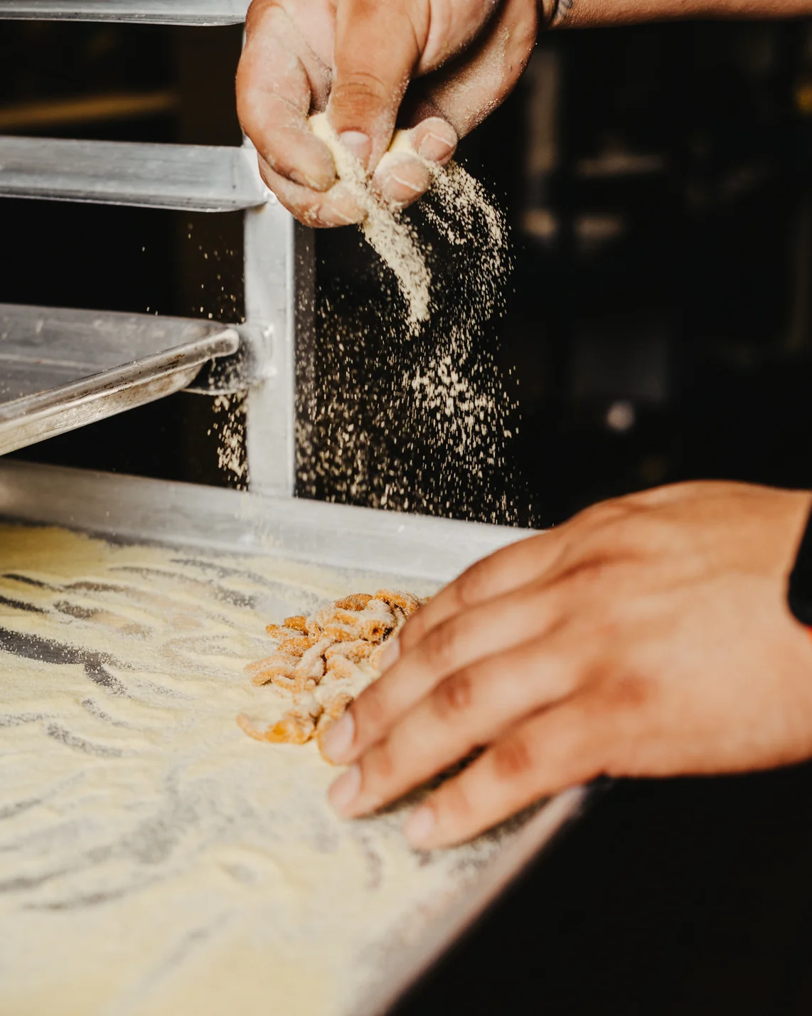 Chef sprinkling flour on a prep surface in a professional kitchen
