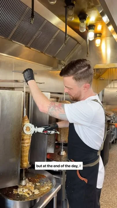 Chef slicing shawarma in a busy kitchen
