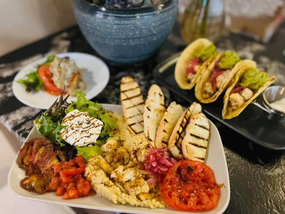 A vibrant plate featuring tacos, grilled chicken, a side salad, and assorted vegetables, arranged artistically on a table.