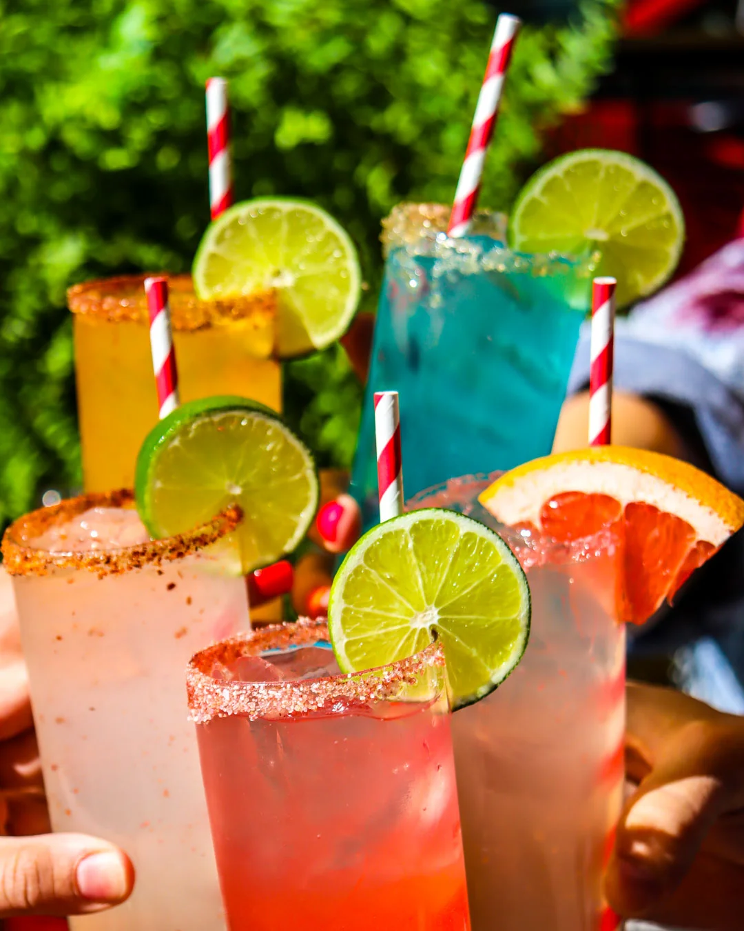 Colorful cocktails with fruit garnishes and striped straws