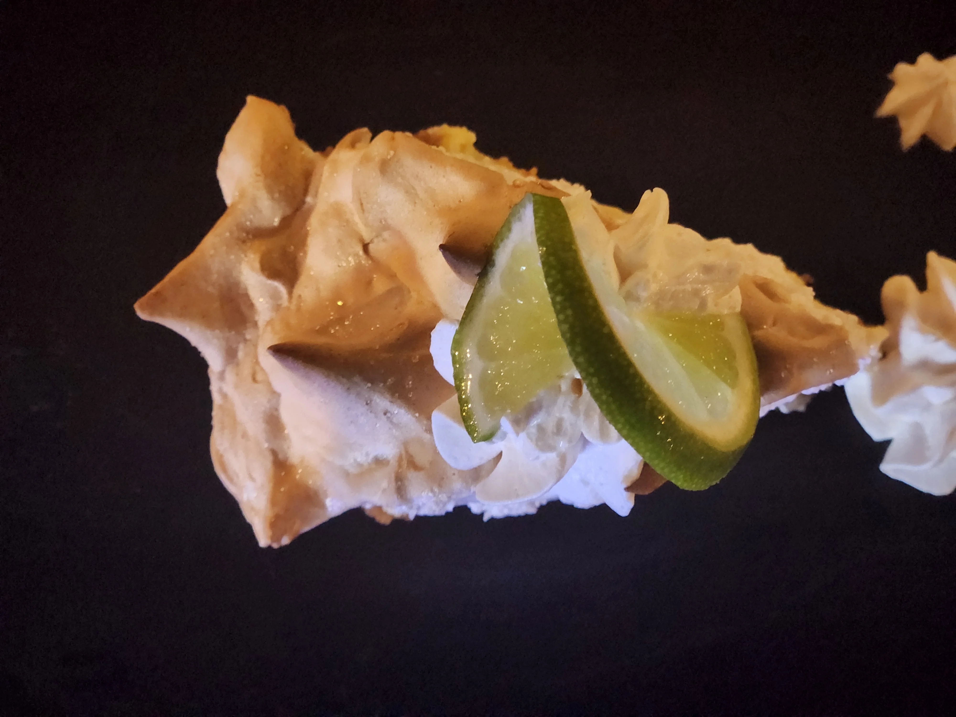 Key lime pie slice with whipped cream and lime garnish