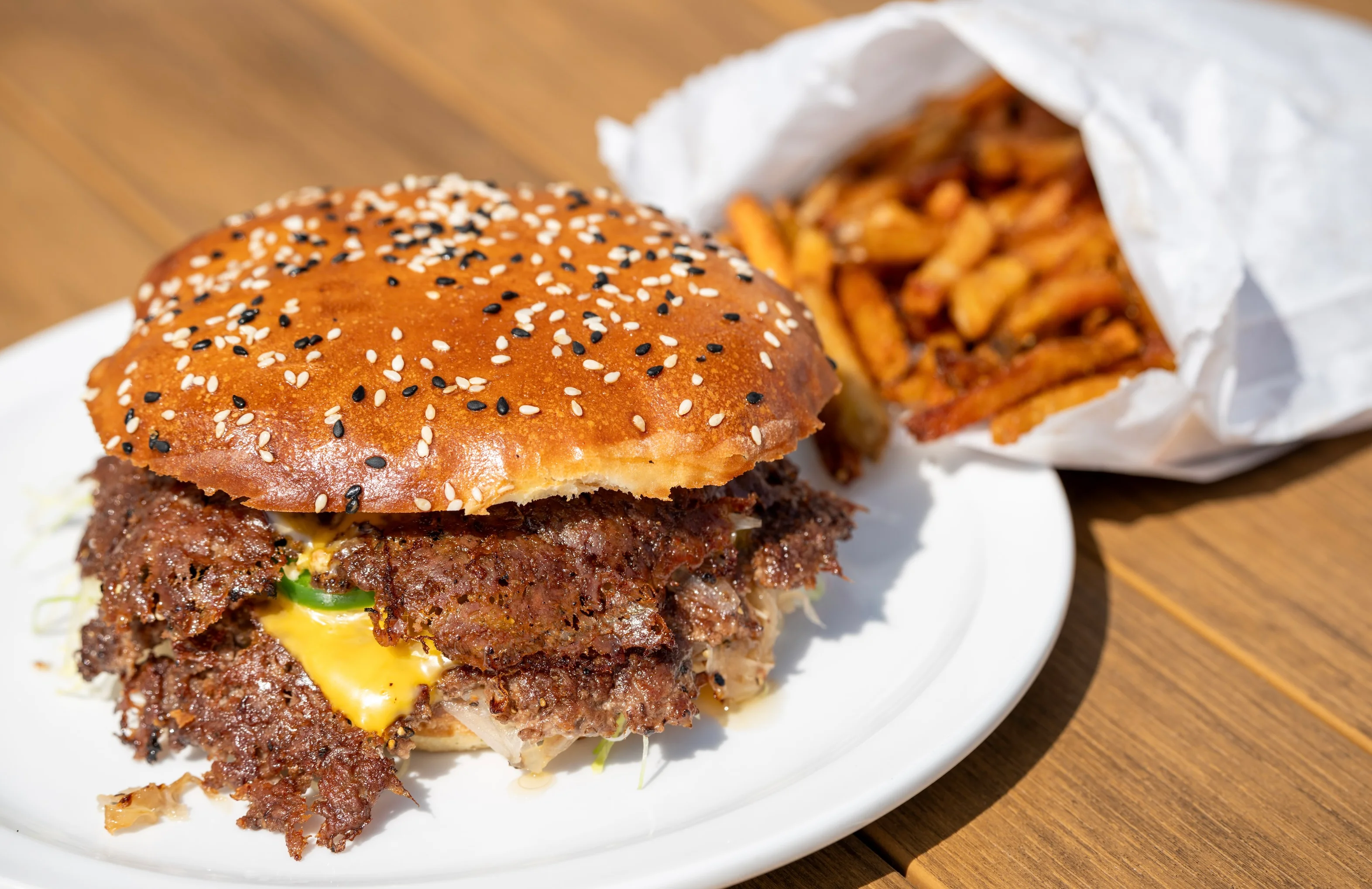 Our Iconic Oklahoma Smash Burger — Ground beef blend patty with onions, American cheese, homemade pickles, shredduce, and Joezauce, served on a homemade sesame seed bun. (No onions available upon request)