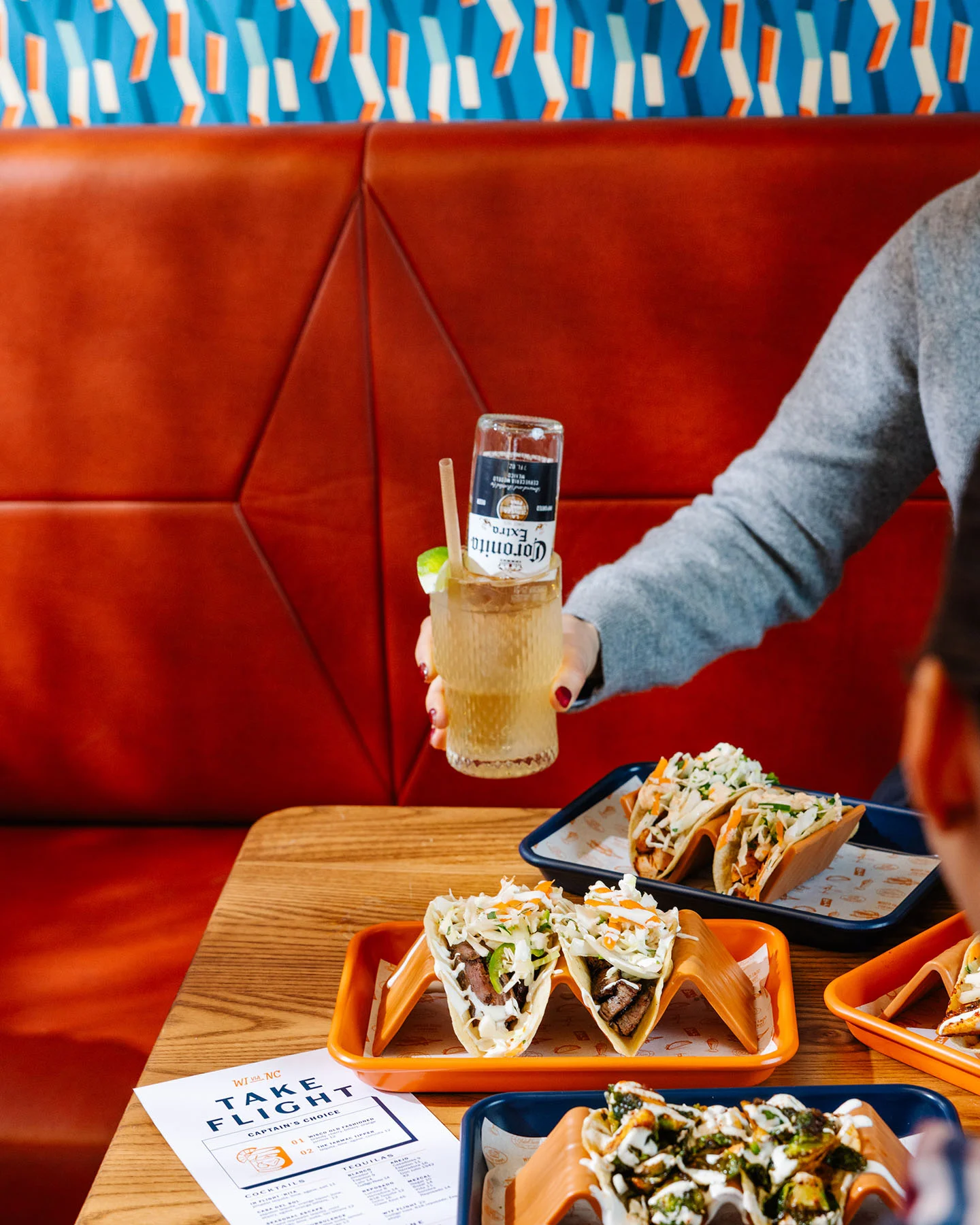 Colorful tacos served with a refreshing drink in a vibrant restaurant setting