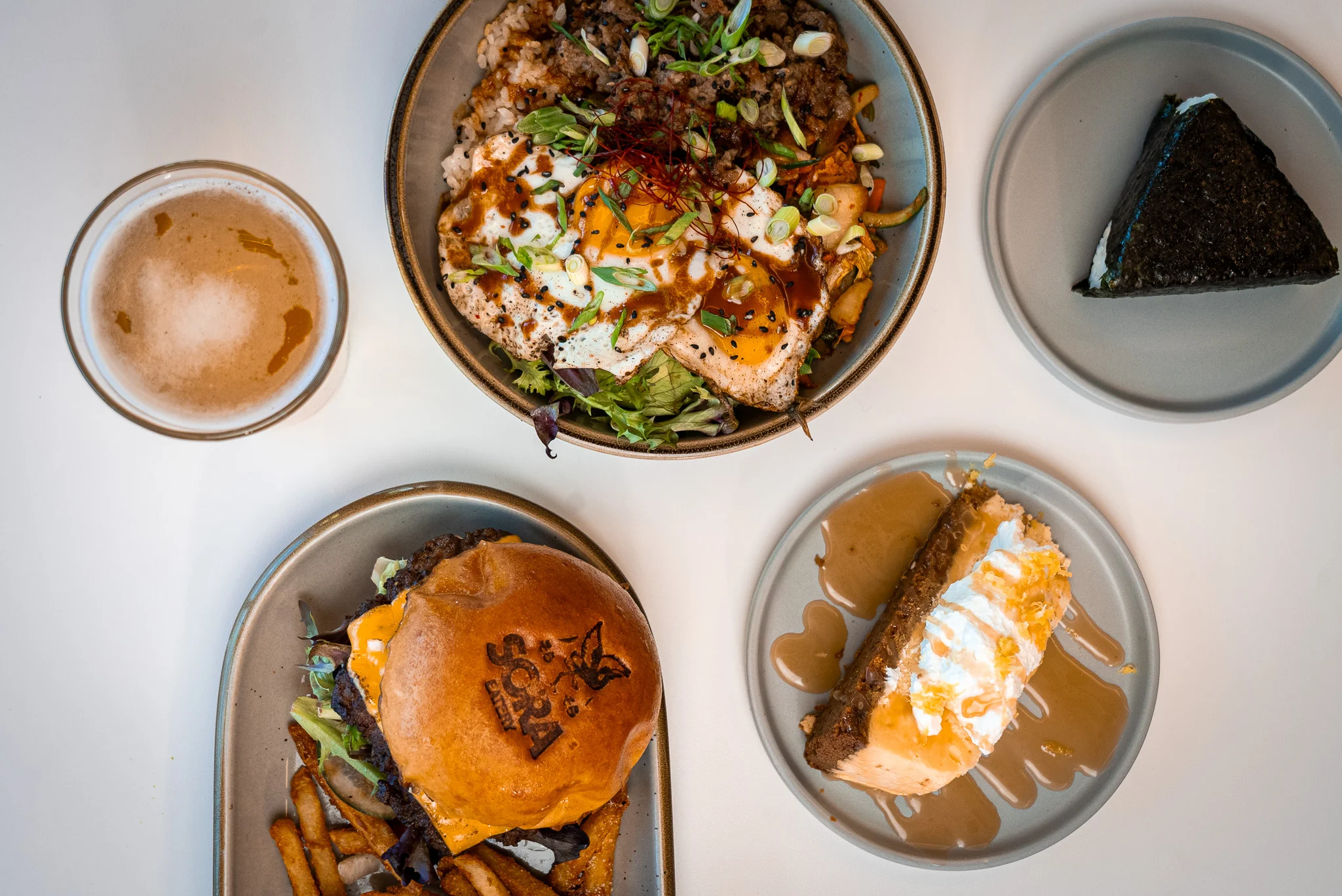 Korean bibimbap topped with fried eggs and a gourmet burger
