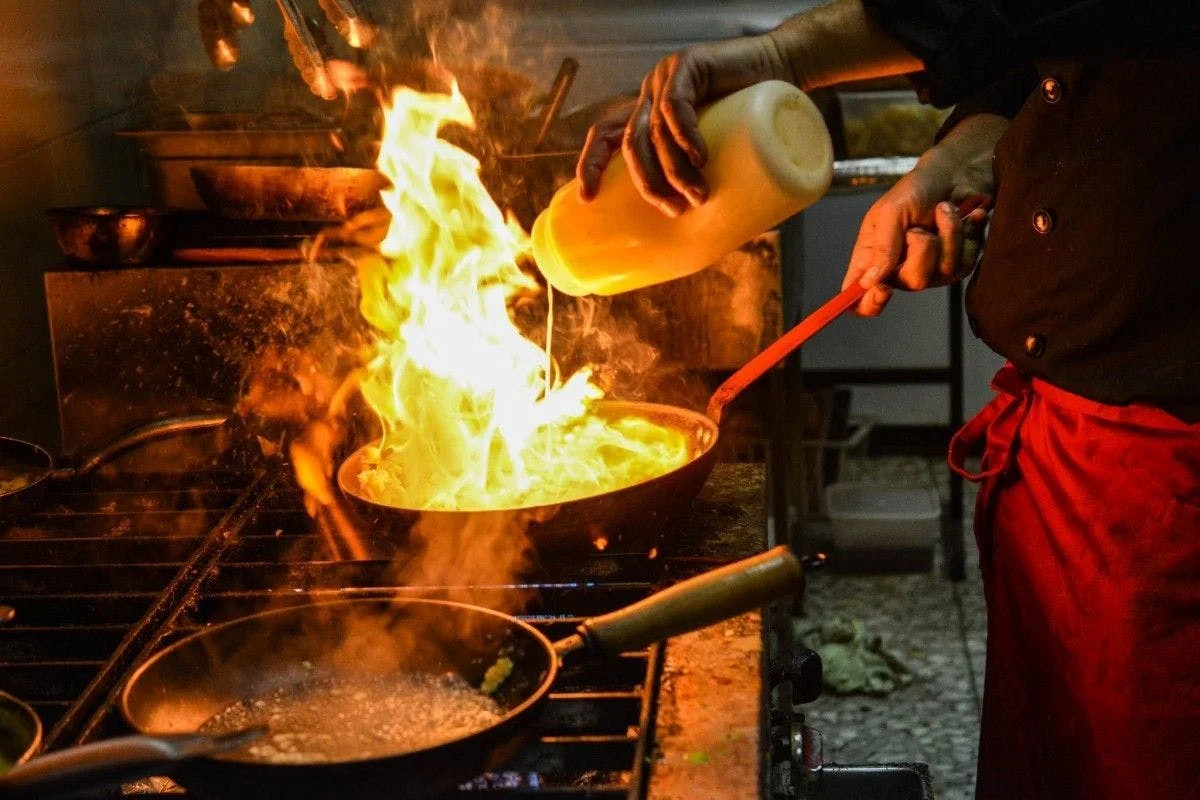 Chef flambéing a dish in a professional kitchen