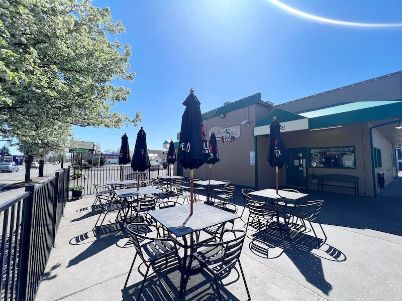 Outdoor dining area with tables and umbrellas on a sunny day
