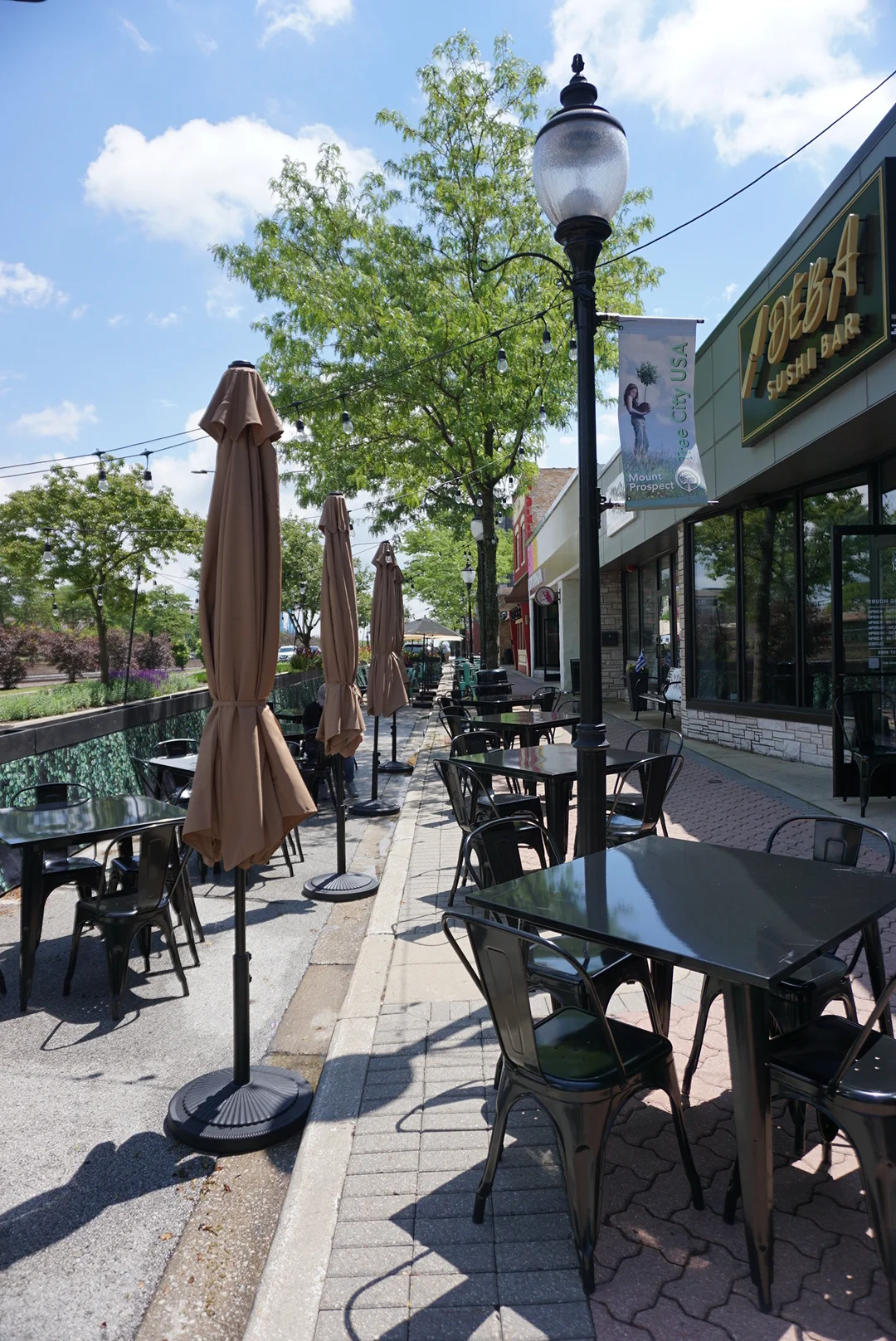 Outdoor dining area with tables and umbrellas at a sushi restaurant.