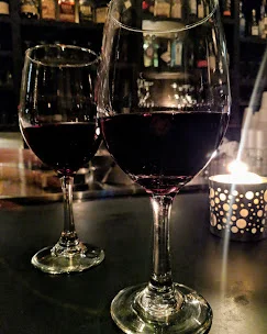 Two glasses of red wine illuminated by a soft candlelight, creating a cozy atmosphere.