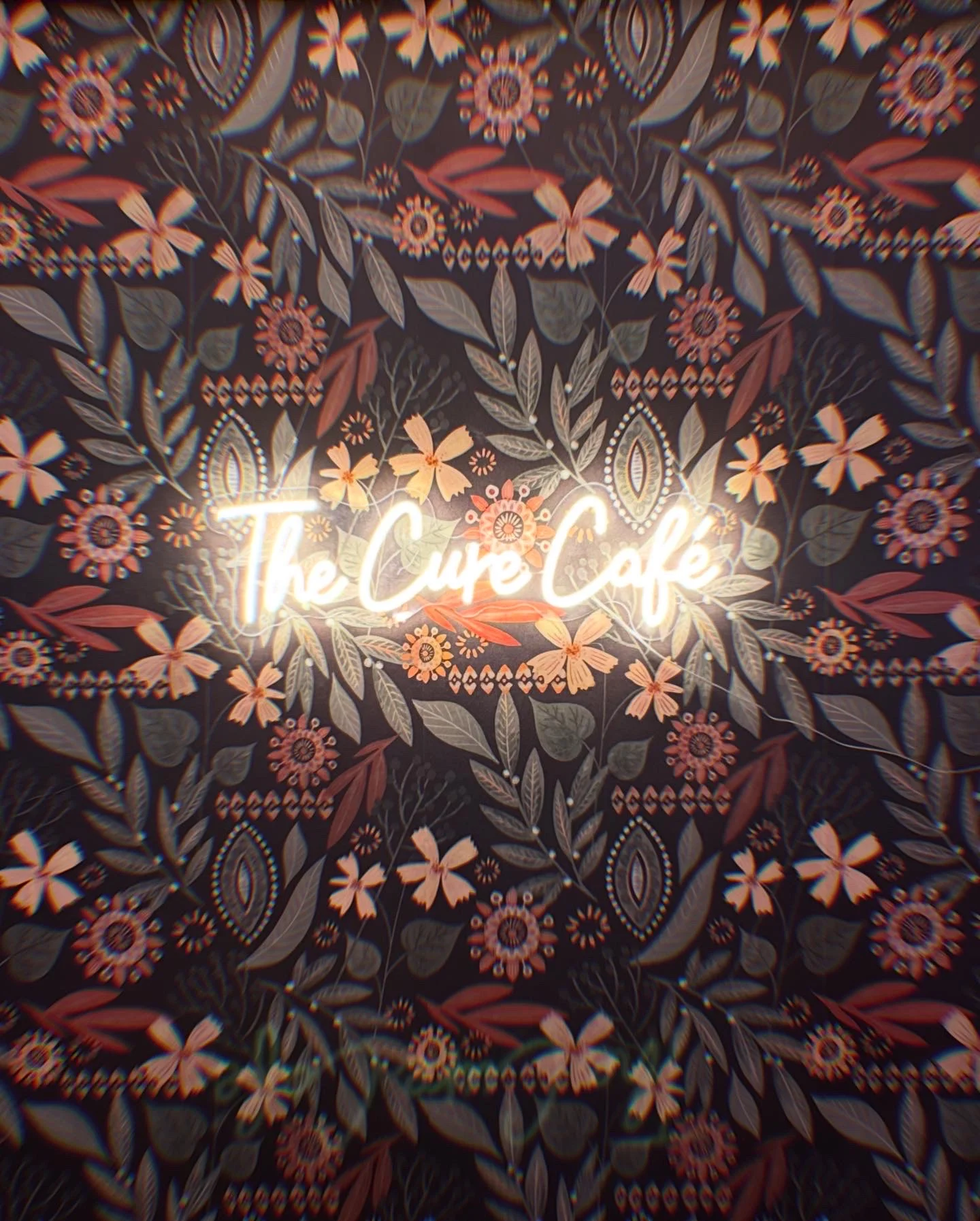 Charming café interior with floral wallpaper and illuminated sign