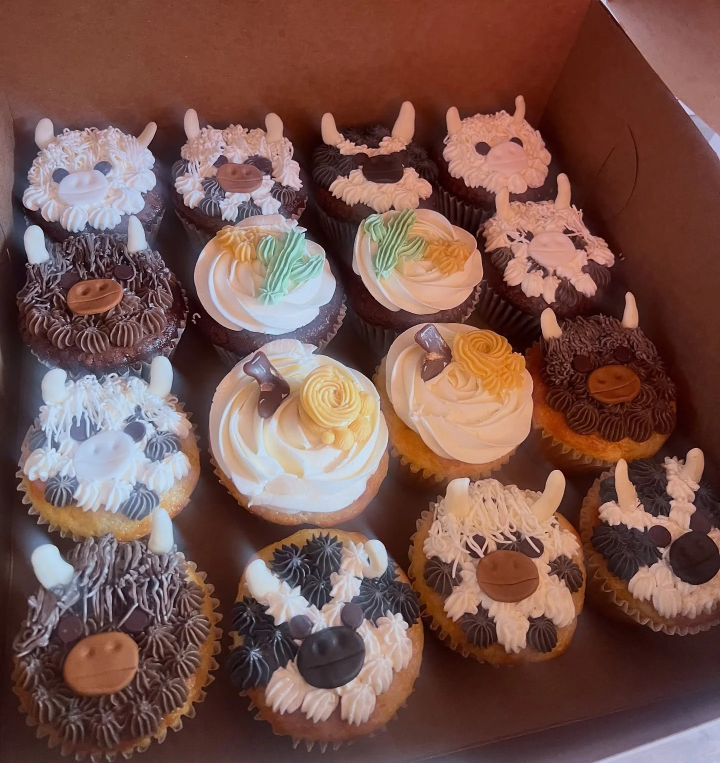 Decorative animal-themed cupcakes in a bakery box