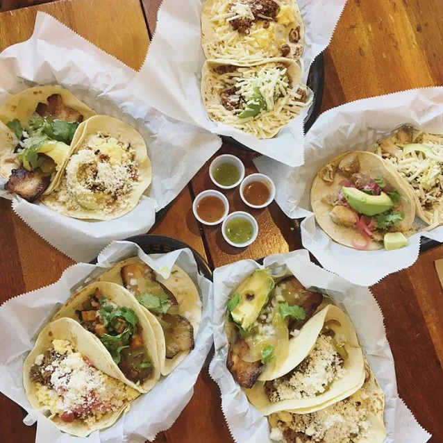 A ring of taco trays with a few cups of salsa in the middle