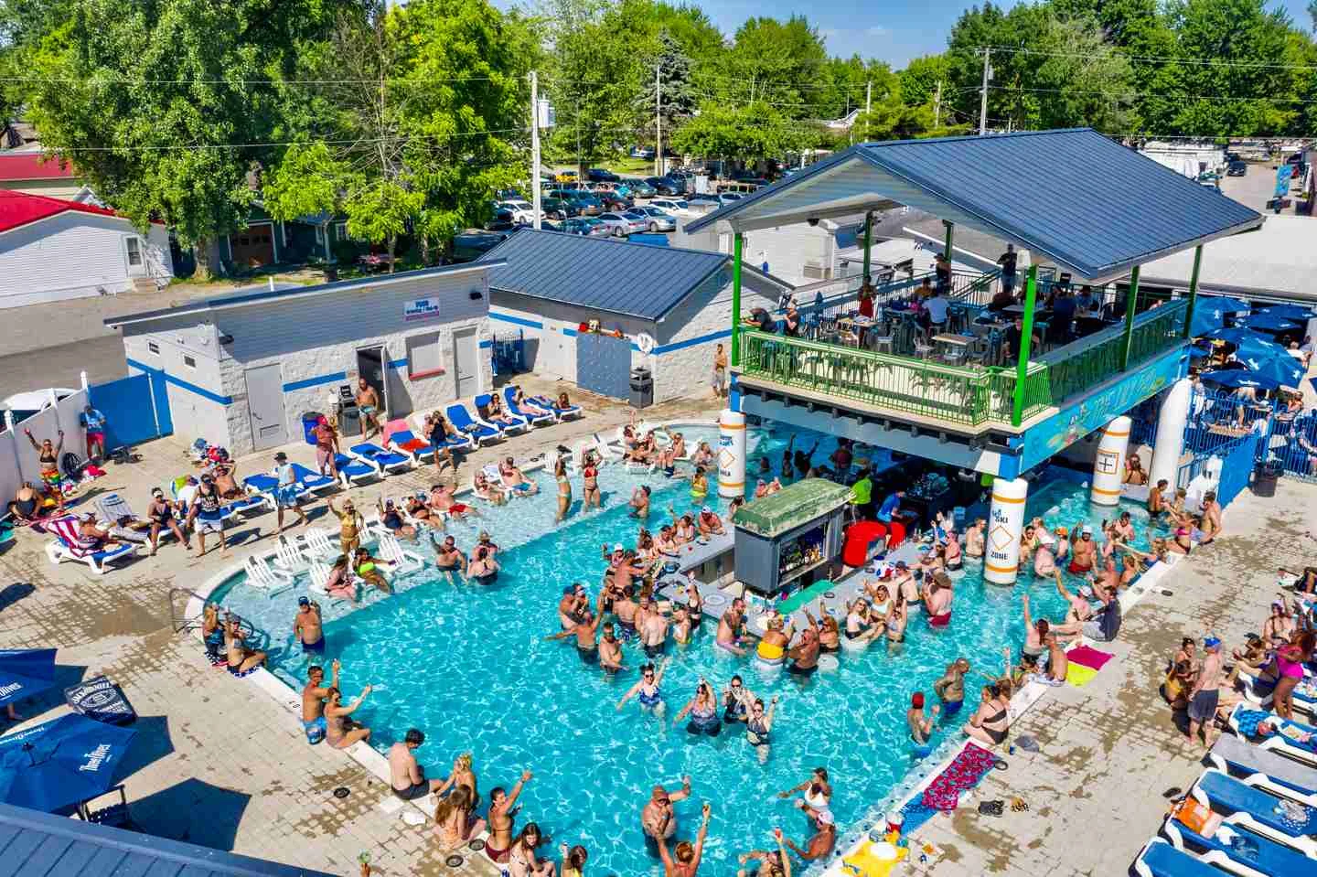 Vibrant pool party scene with guests enjoying drinks and sunbathing