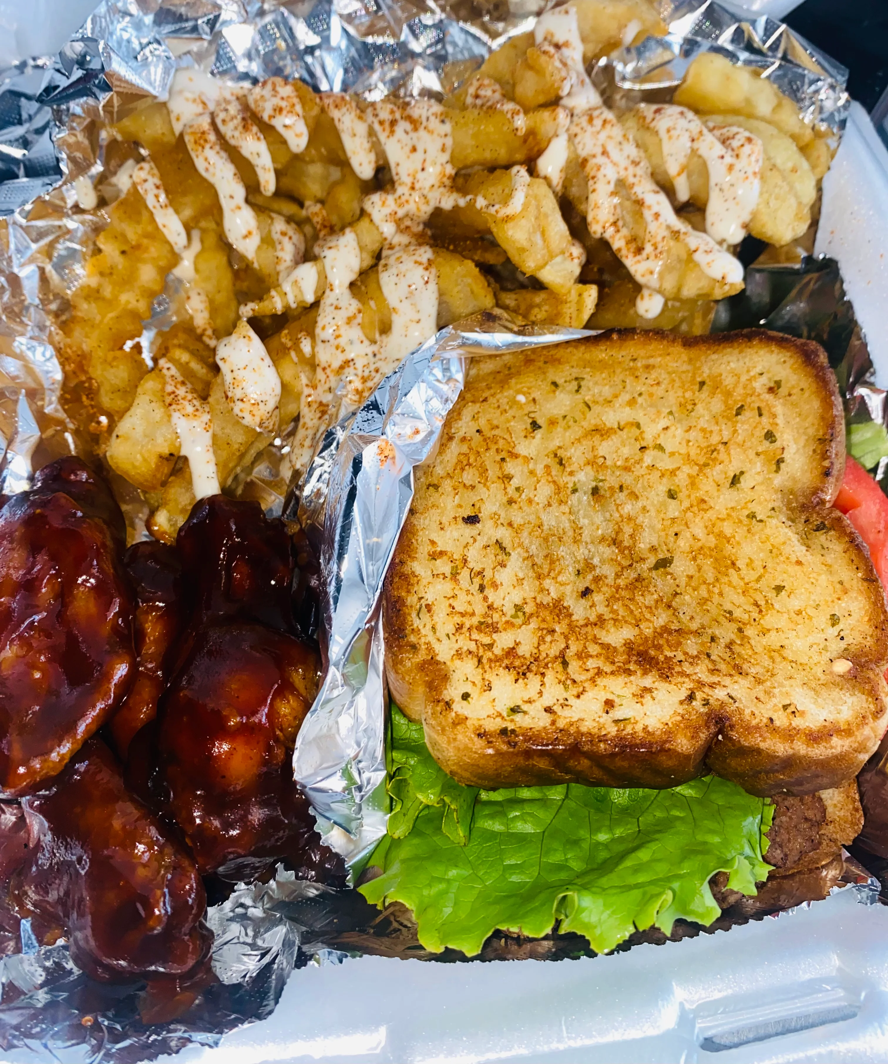 Two containers of food featuring fried chicken sandwiches, crinkle-cut fries, and additional fried chicken. The sandwiches include lettuce and cheese.