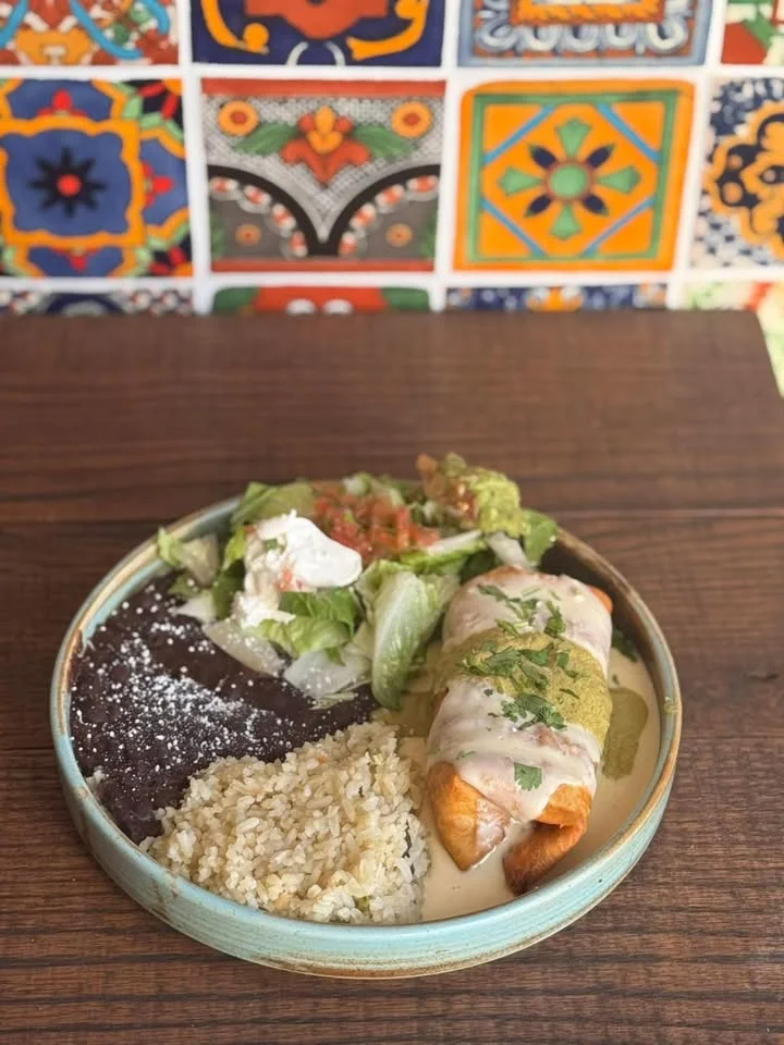 Mexican enchiladas with rice and beans on a colorful tiled background