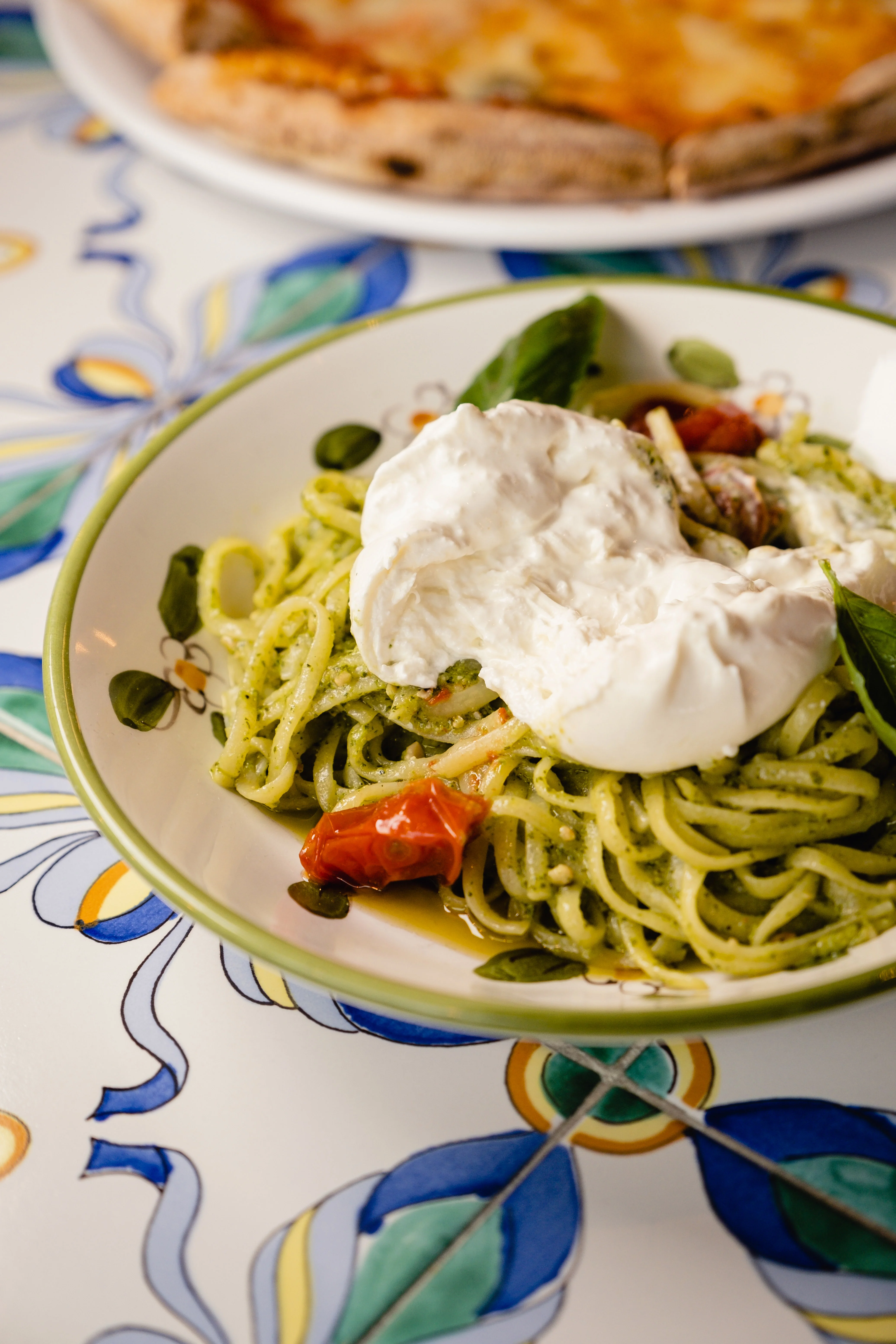 Pasta al pesto with burrata in a vibrant Italian restaurant setting