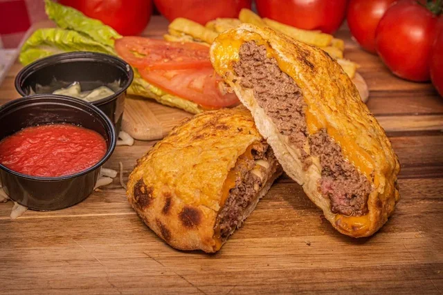 Cheesy beef calzone served with marinara sauce