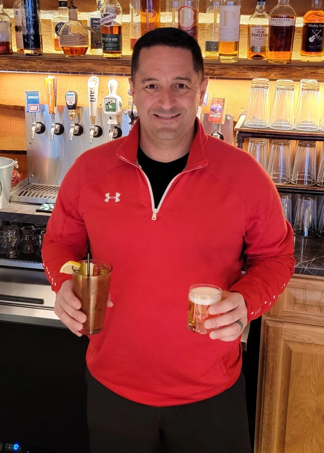 Bartender holding cocktails at a rustic bar
