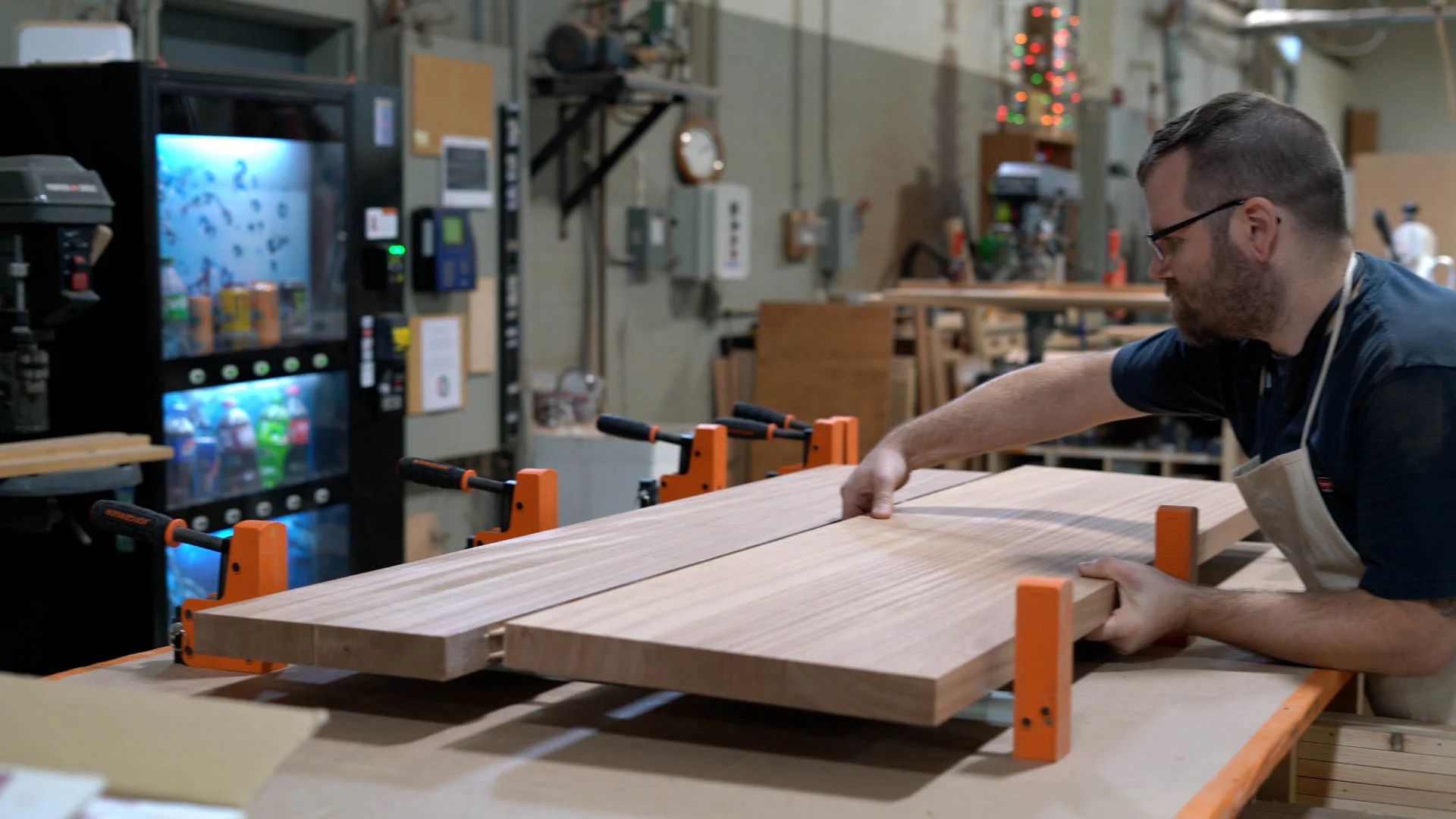 Woodworker assembling a large wooden tabletop in a workshop