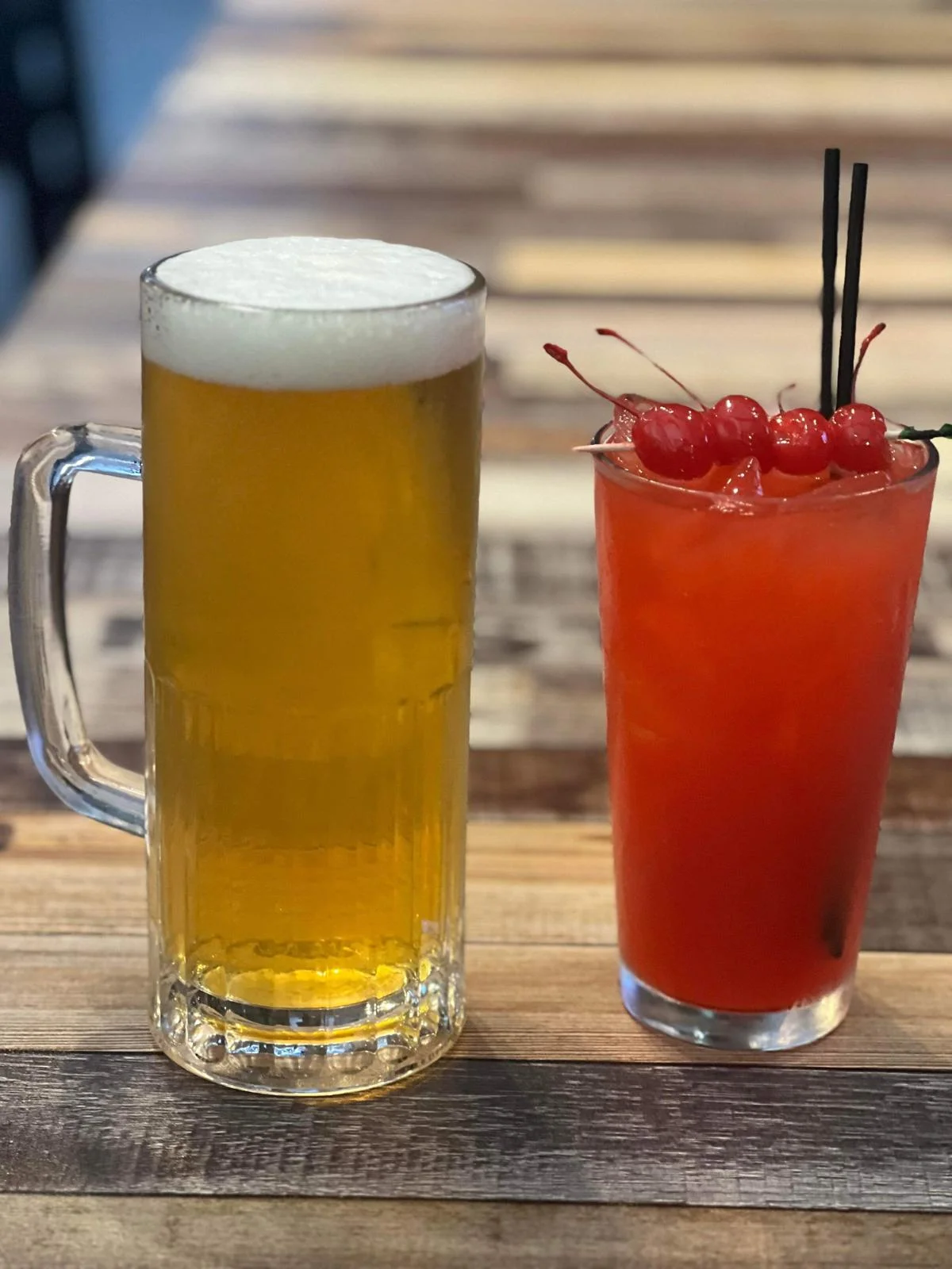 Refreshing beer and cocktail with cherries on a rustic wooden table
