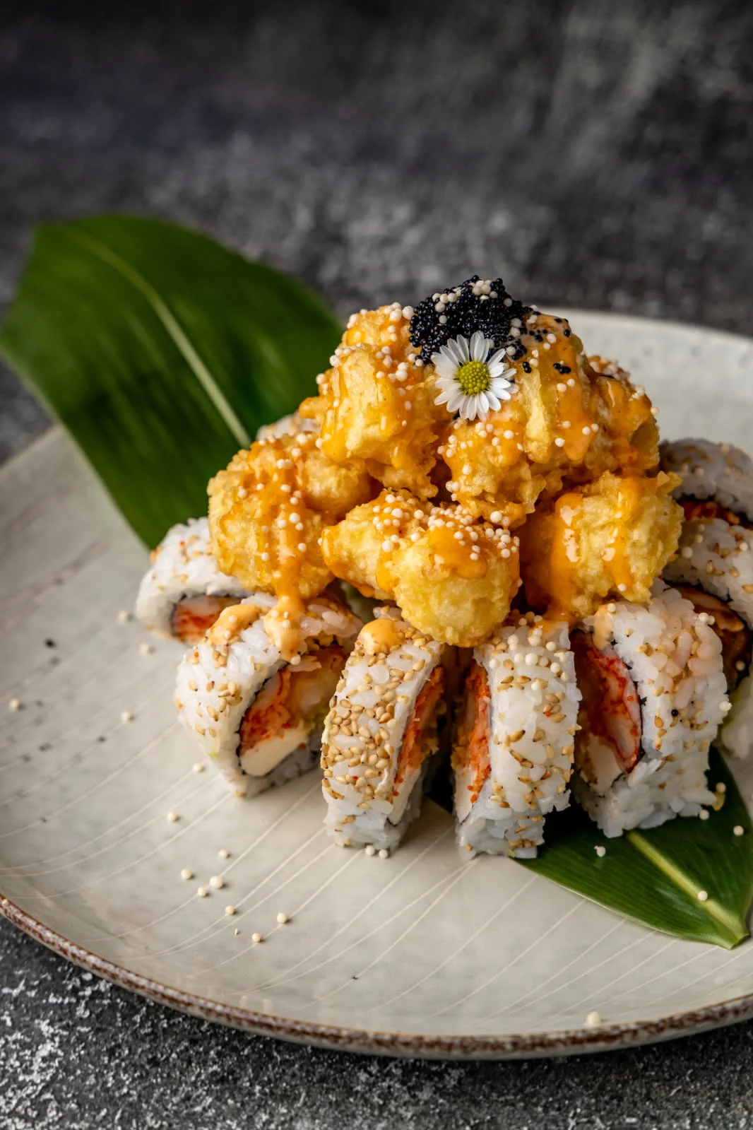 Japanese sushi roll topped with tempura and spicy sauce