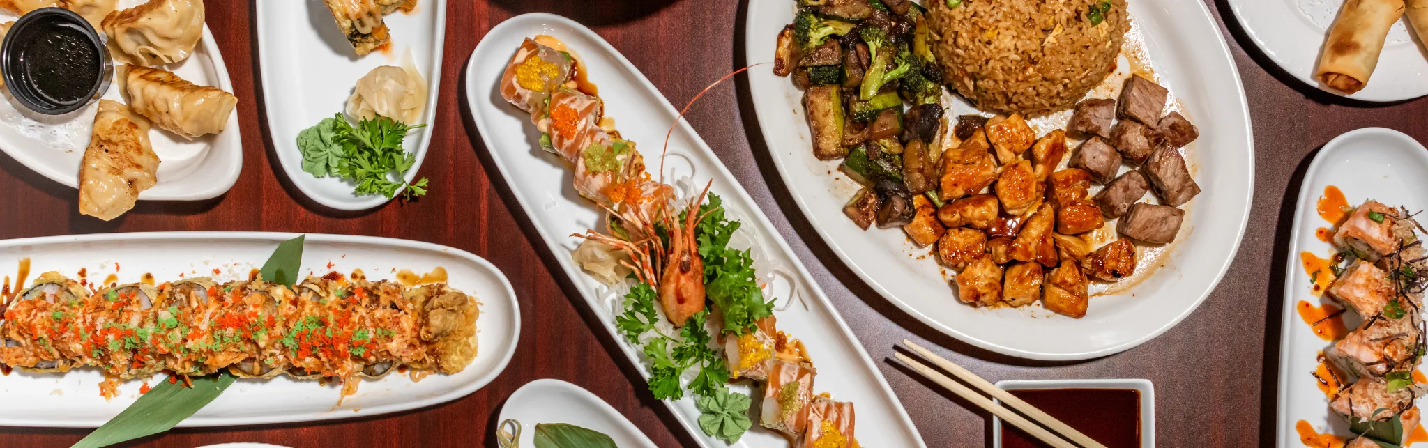 Assorted sushi and Asian dishes on a wooden table