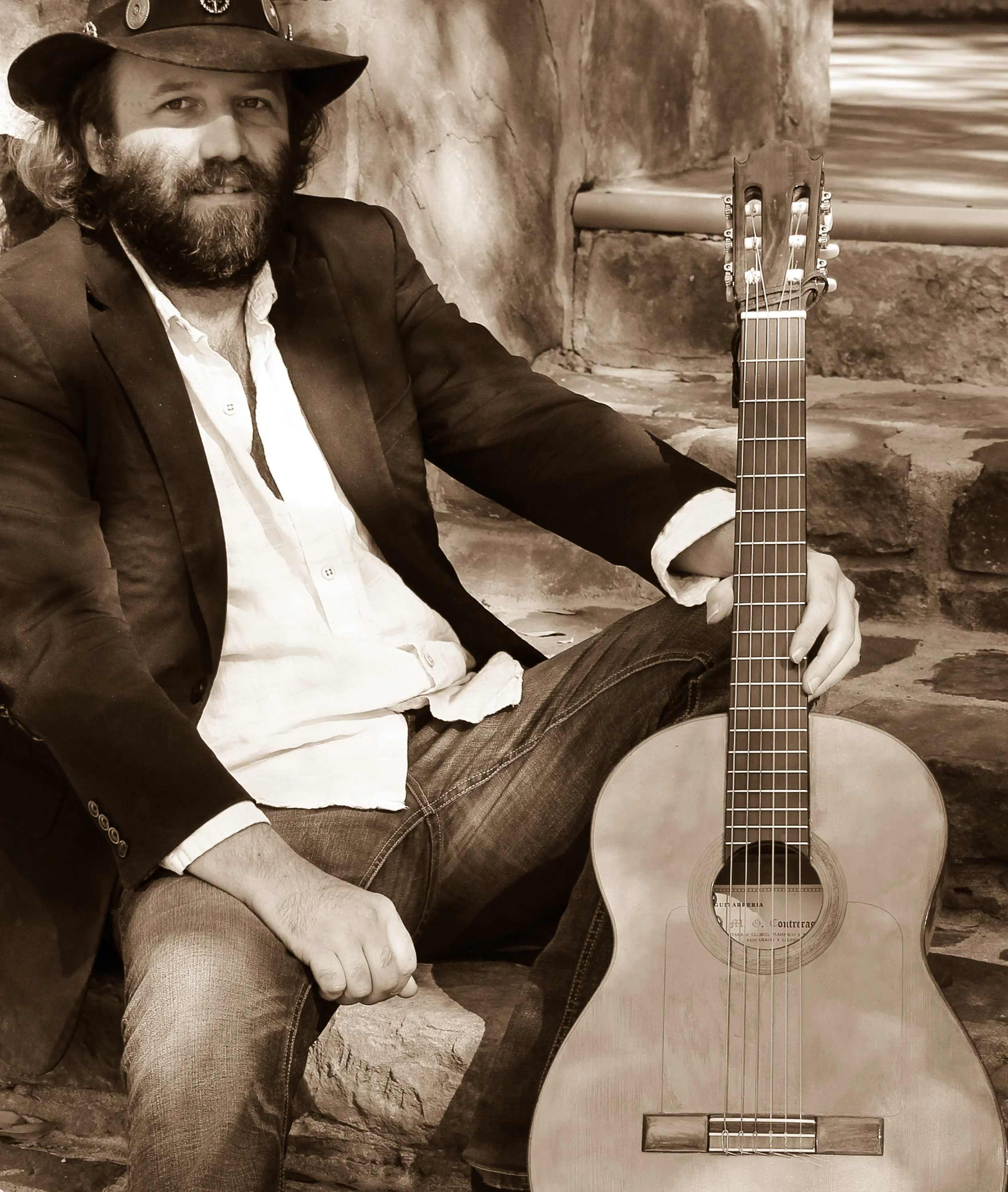 Musician seated with guitar in a rustic outdoor setting