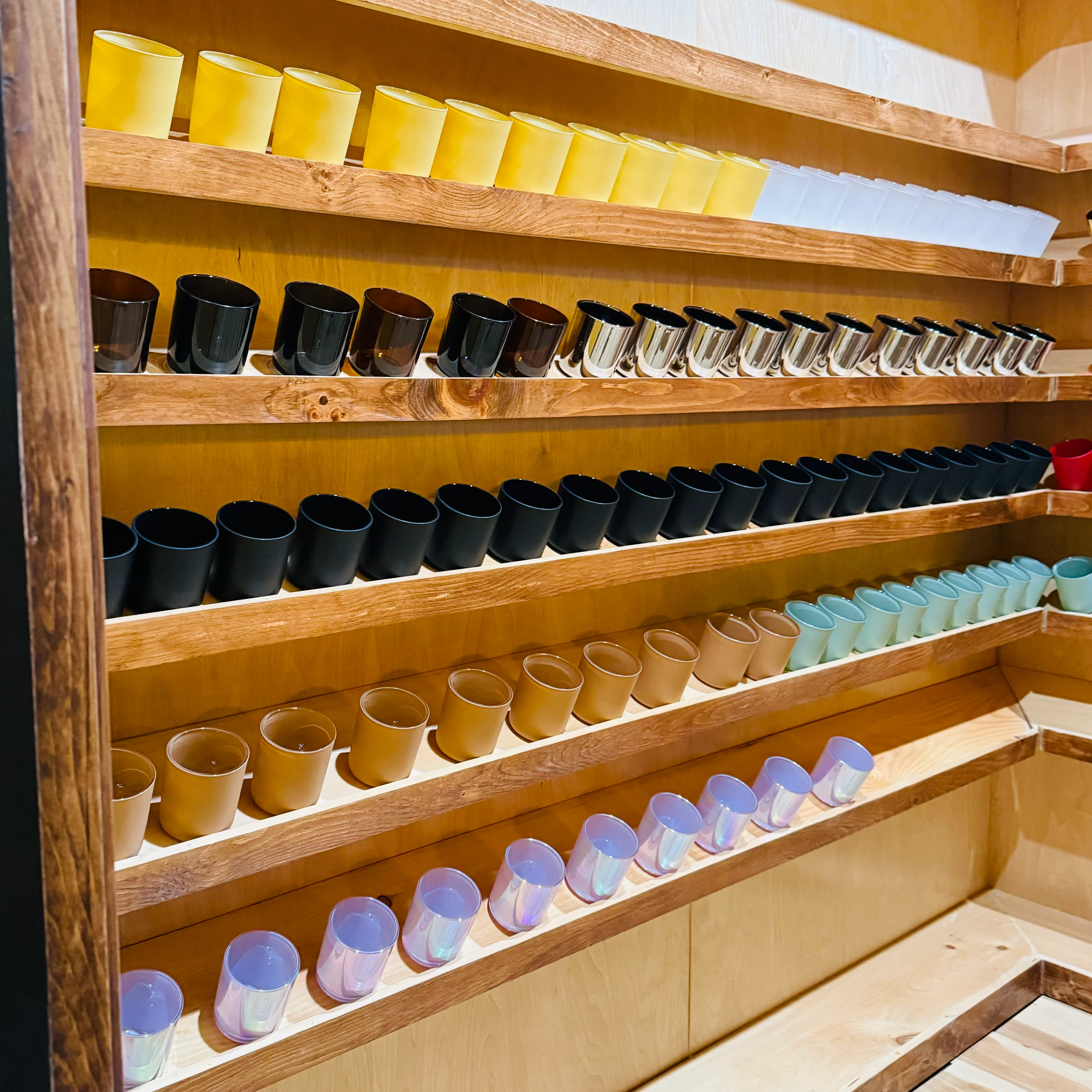 Colorful display of assorted candle holders on wooden shelves